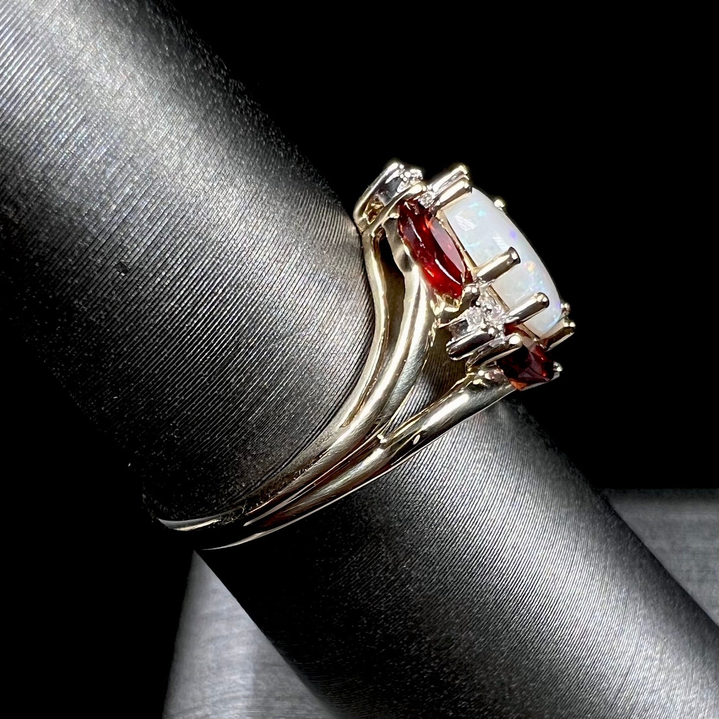 A ladies natural opal ring in yellow gold. The opal is surrounded by red marquise cut garnets and diamonds.
