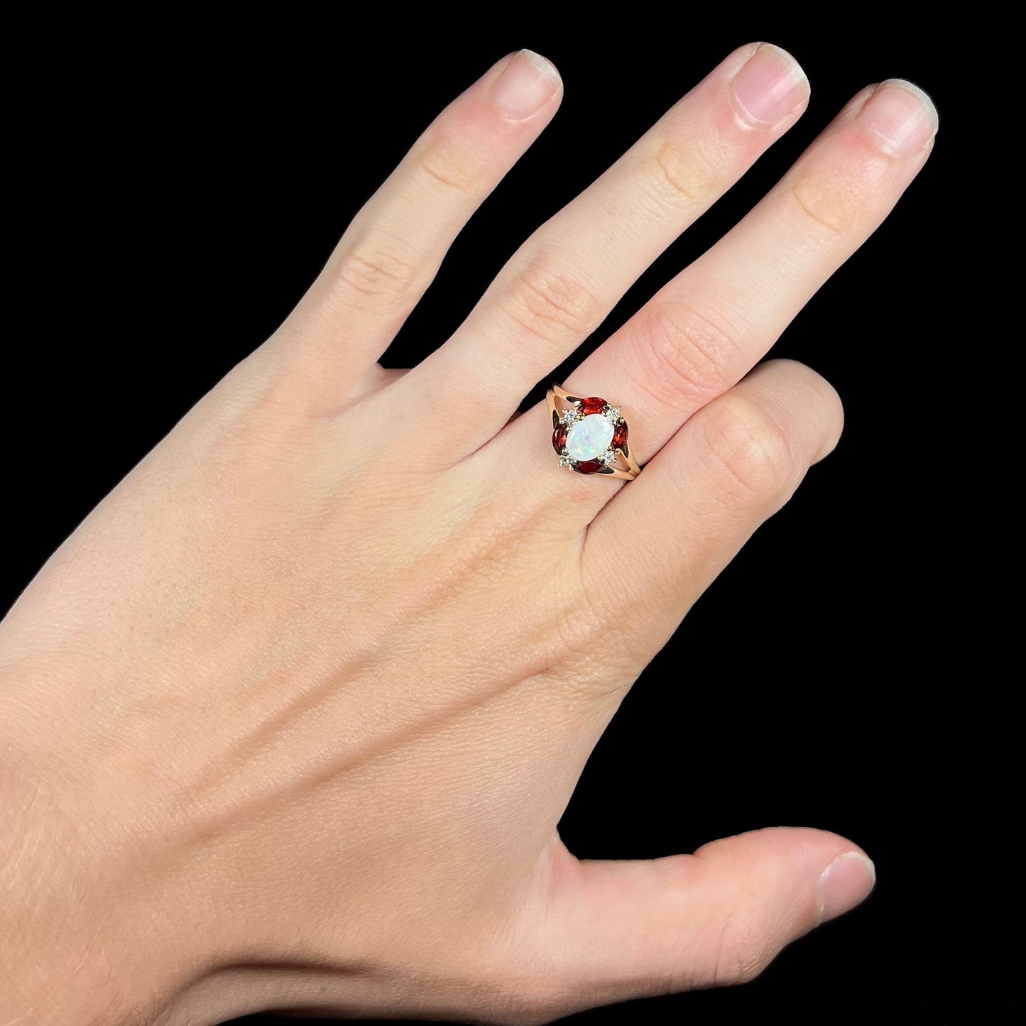 A ladies natural opal ring in yellow gold. The opal is surrounded by red marquise cut garnets and diamonds.