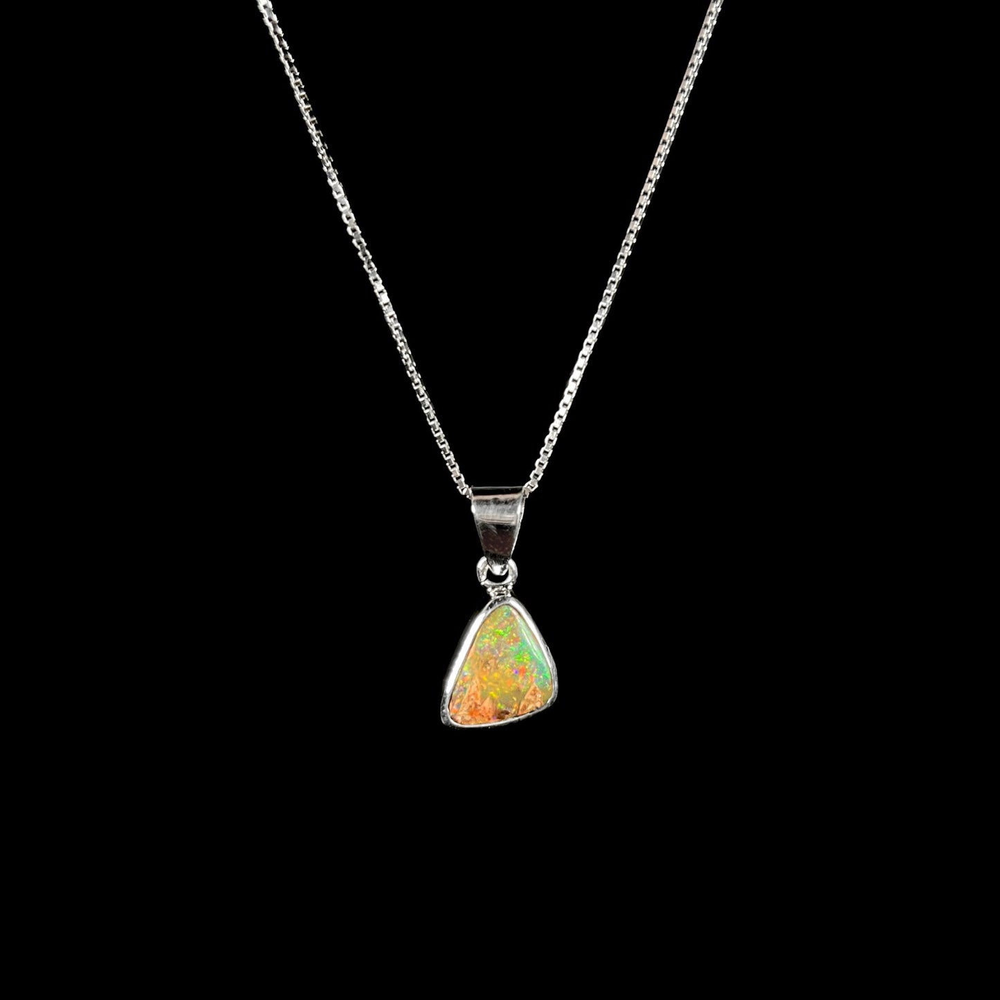 A sterling silver boulder opal necklace on a box chain. The opal twinkles bright red, green, and blue colors.