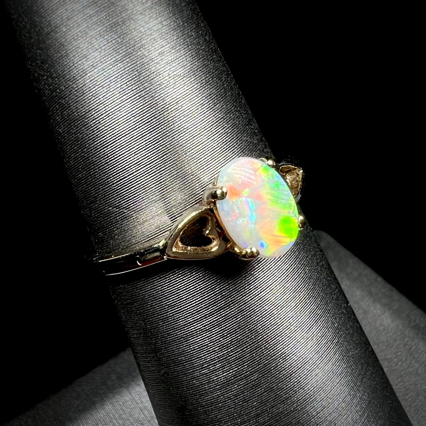 A dainty yellow gold ring mounted with a vivdly bright red Australian opal. The ring has two heart shaped designs.