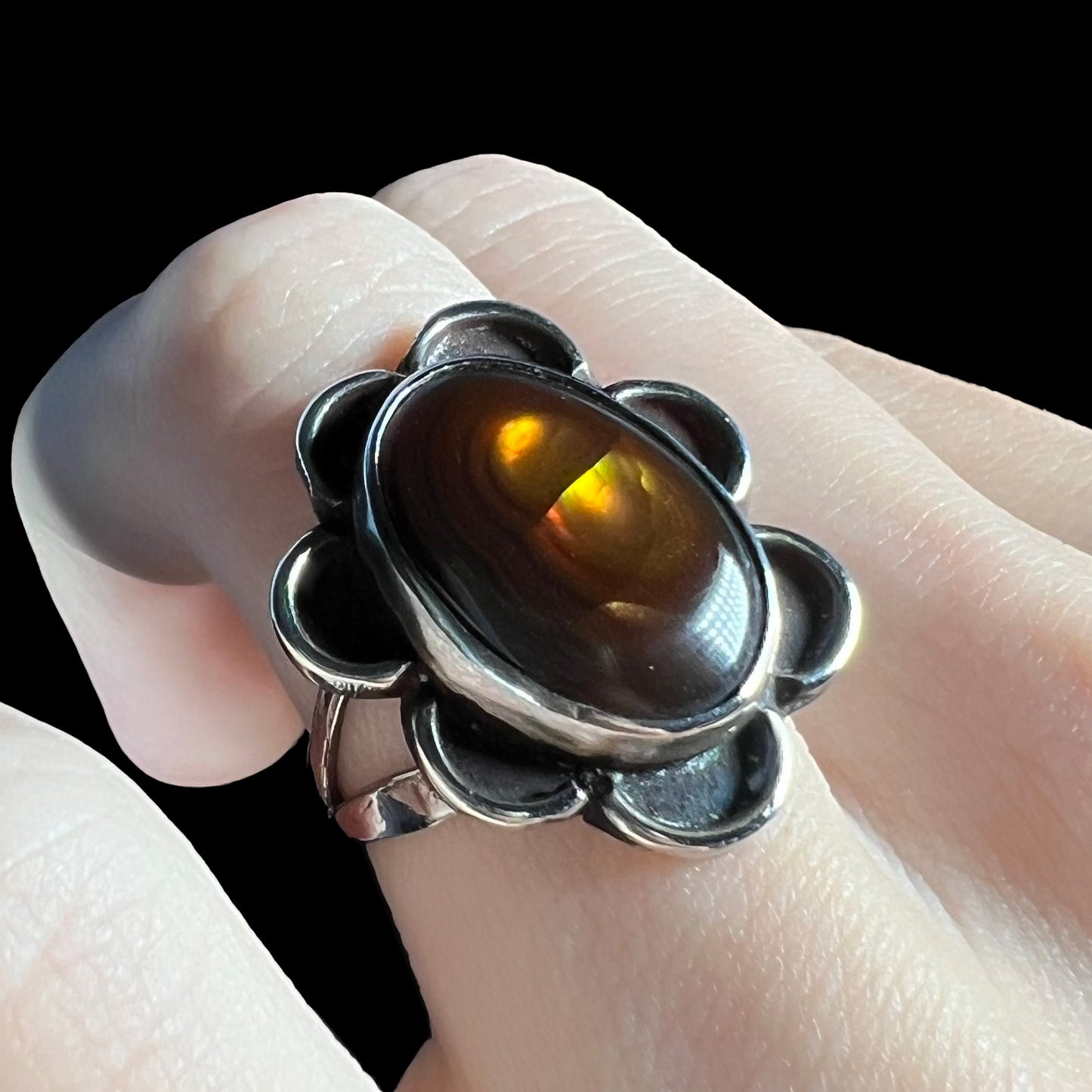 Opposite angle of ring with visible yellow, orange, and green iridescence.