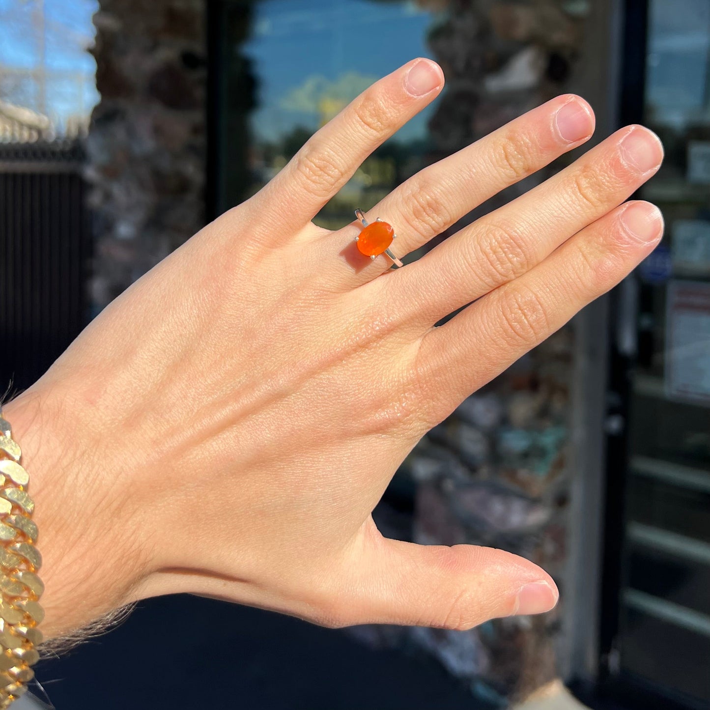A silver solitaire ring set with a natural, faceted oval cut Mexican fire opal. The stone is a bright orange color.