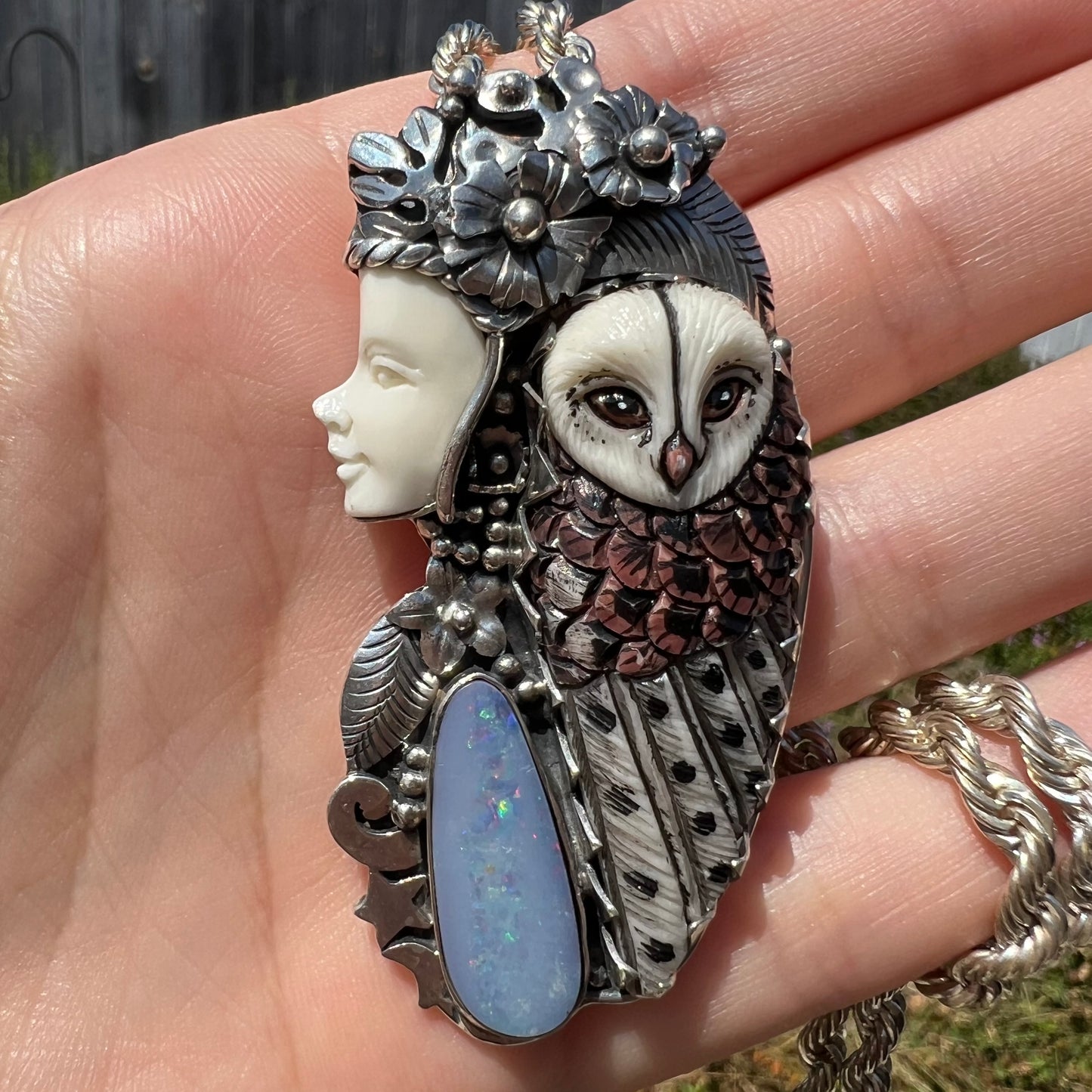 Sunlit shot of woman and owl necklace with a nature-inspired motif, made from silver, bone, and an opal doublet.