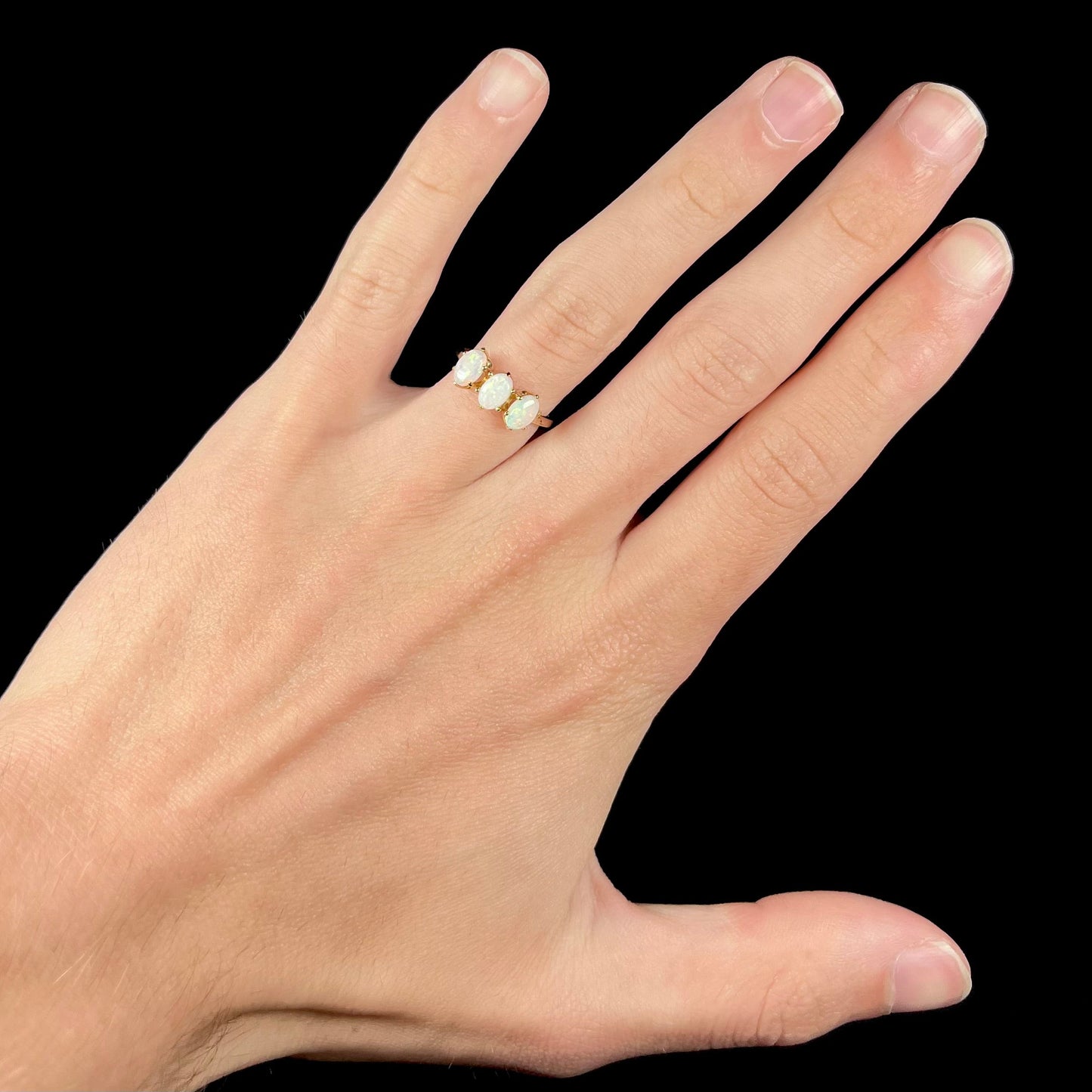 A vintage yellow gold ring mounted with three oval cut white Australian opals.