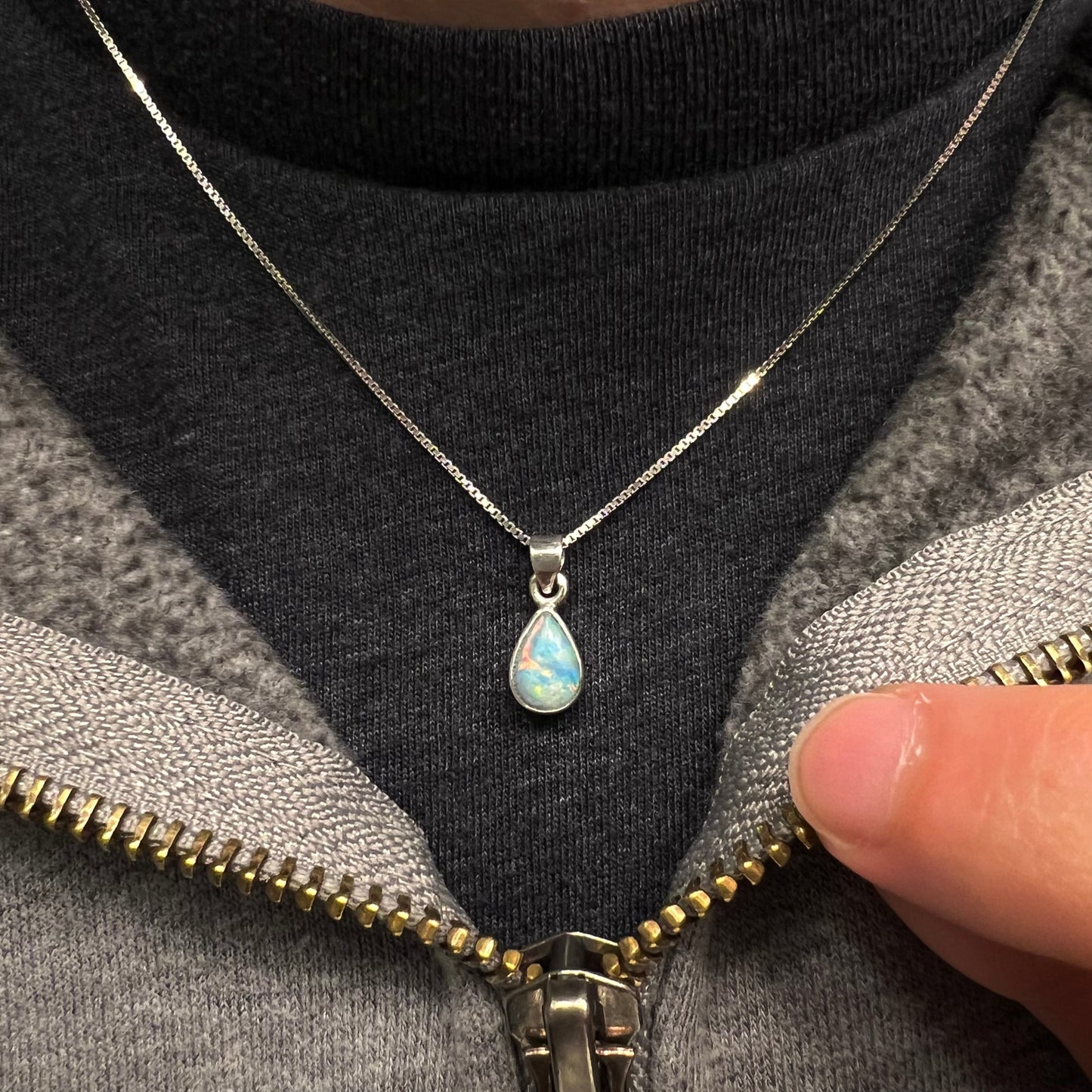 A dainty, sterling silver necklace bezel set with a natural, pear shaped opal stone.