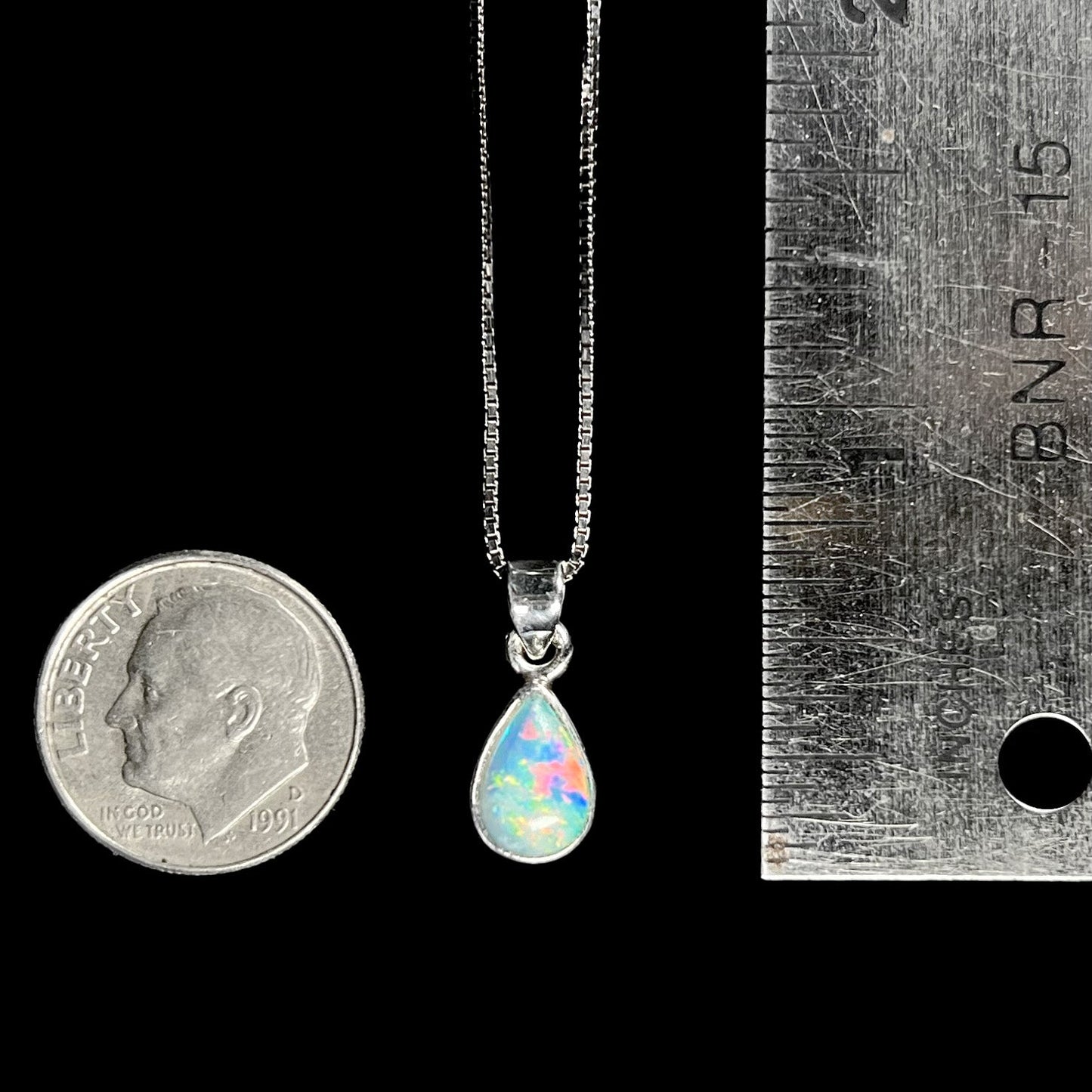 A dainty, sterling silver necklace bezel set with a natural, pear shaped opal stone.
