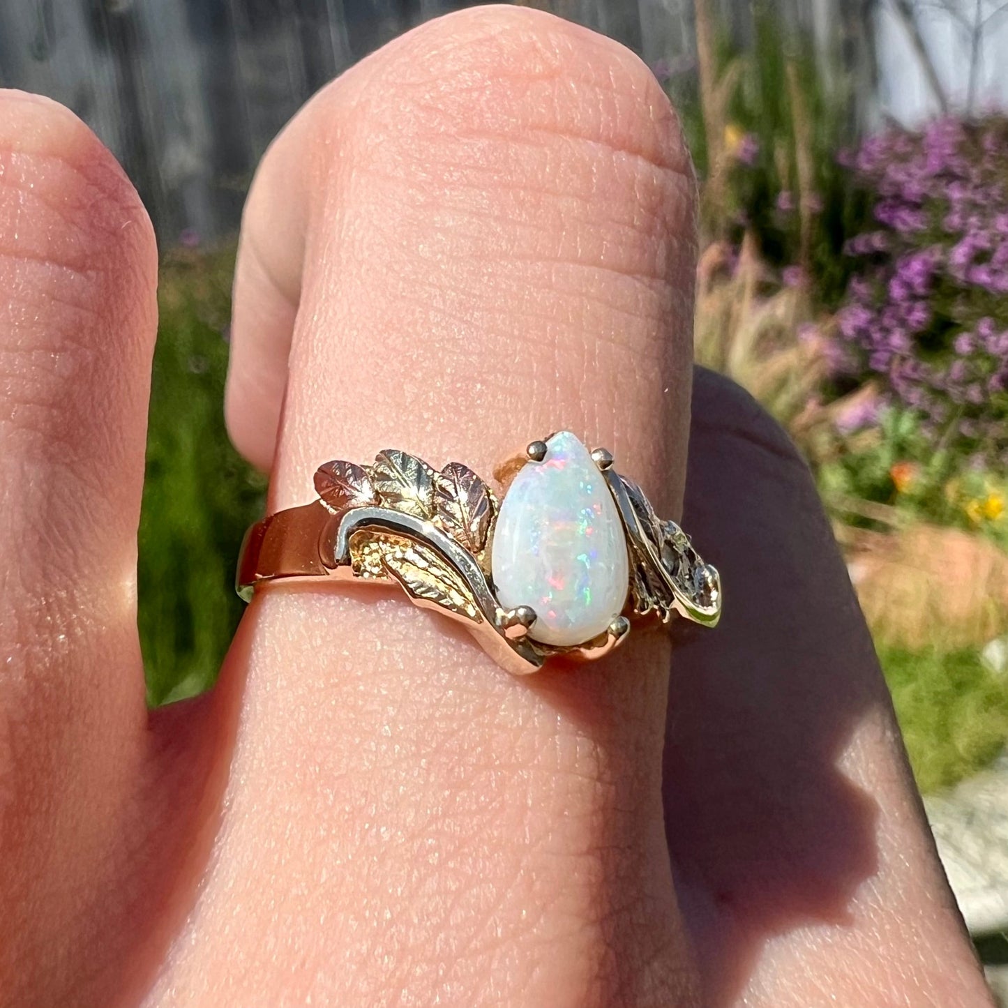 A ladies' two-tone yellow and rose Black Hills gold opal and diamond ring. The opal is a pear shaped cabochon.
