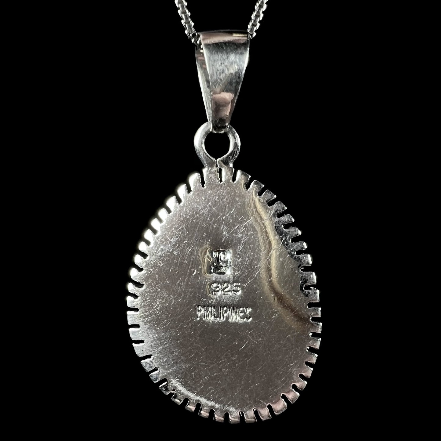 The back side of a Southwest-style sterling silver pendant signed with an artist's initials, "925", and "PHILIPINES".