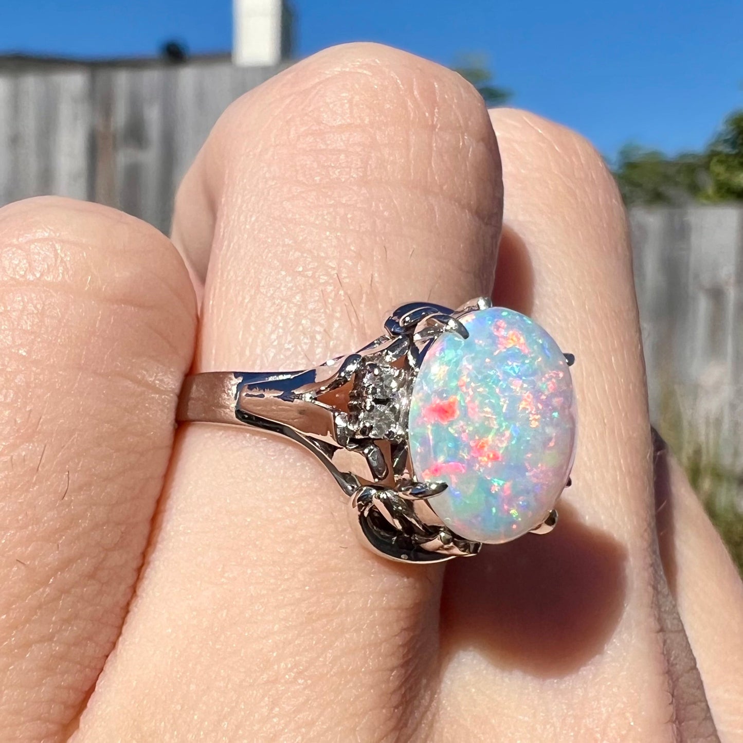 A platinum and diamond ring prong-set with an Australian opal. The opal has pink color play.
