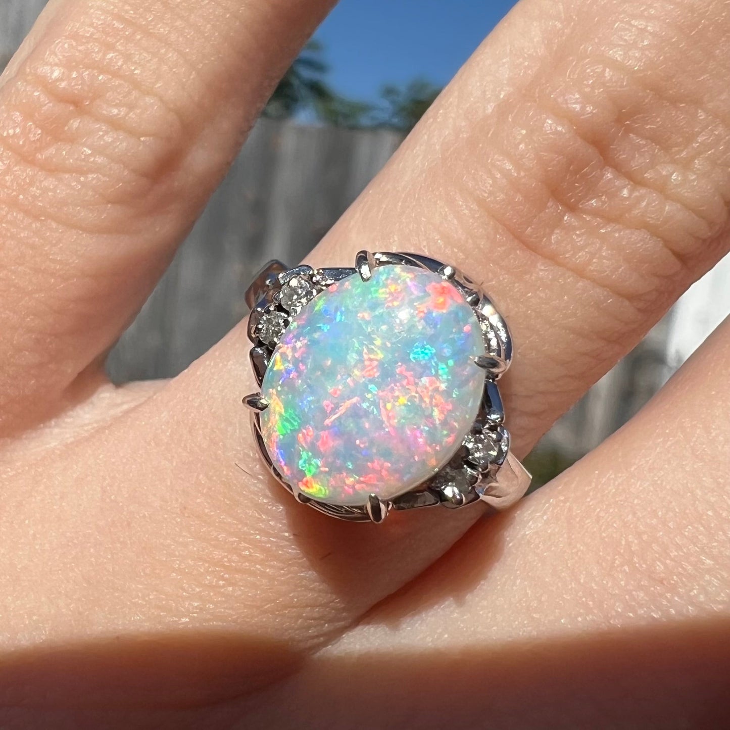 A platinum and diamond ring prong-set with an Australian opal. The opal has pink color play.