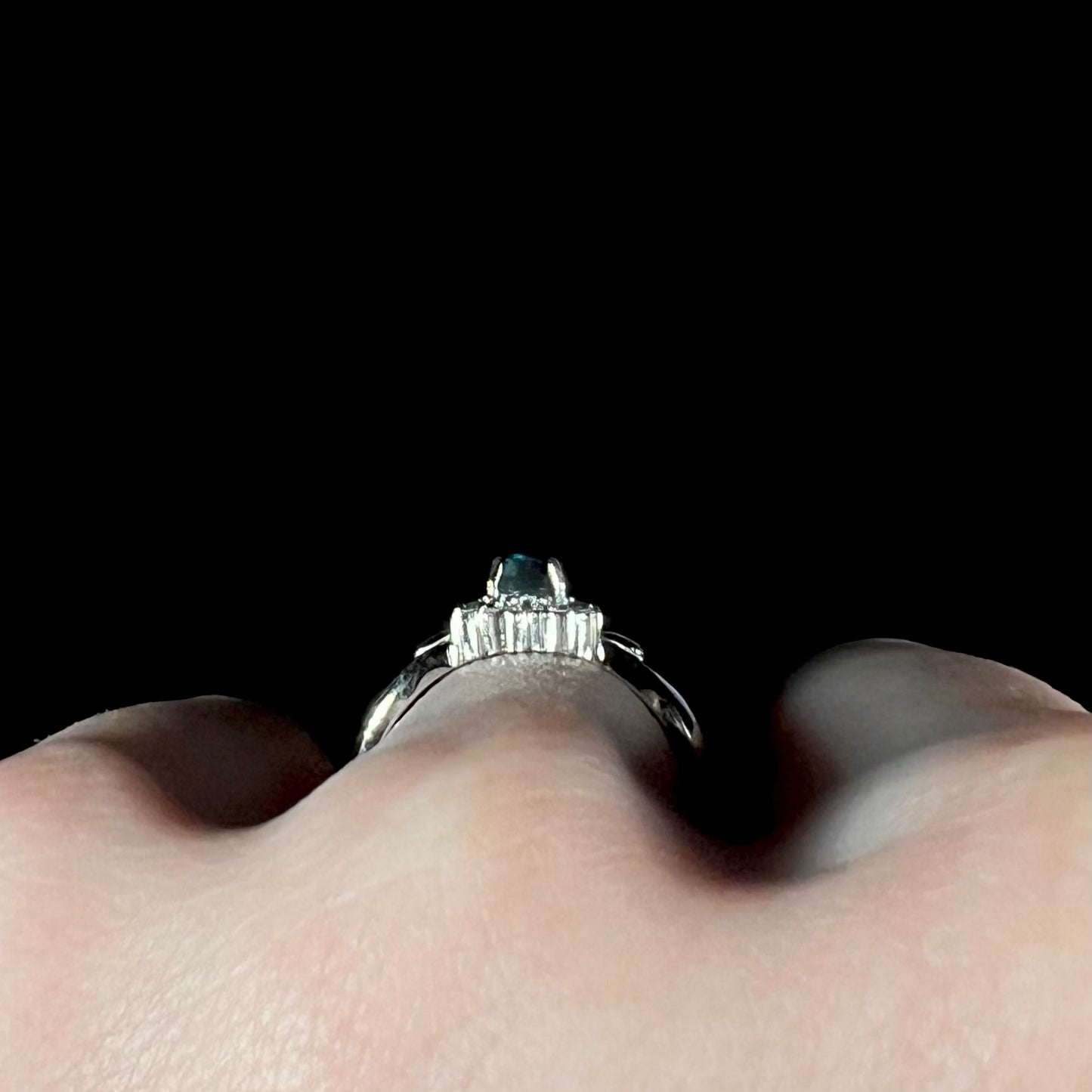 Gallery view of platinum black opal and diamond halo ring worn on finger.