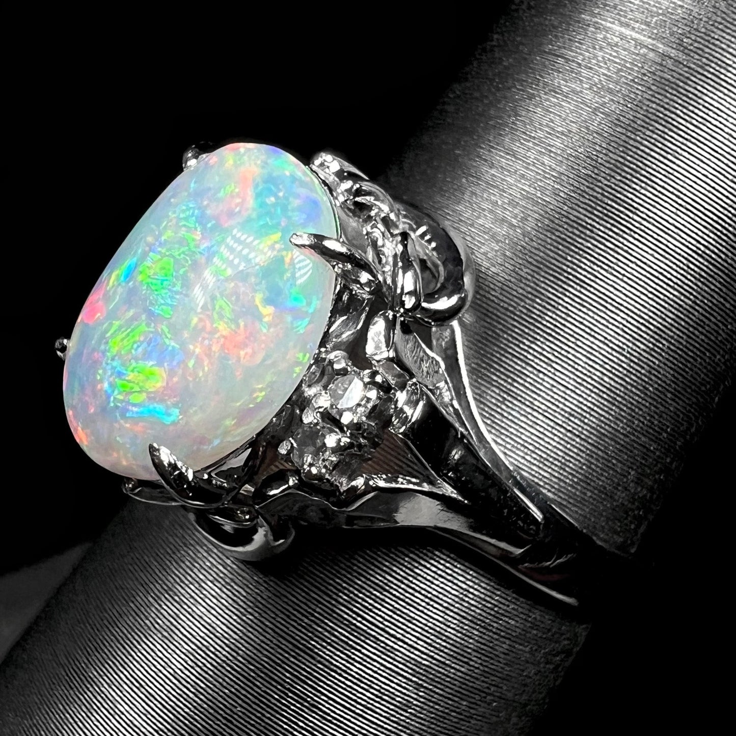 A platinum and diamond ring prong-set with an Australian opal. The opal has pink color play.