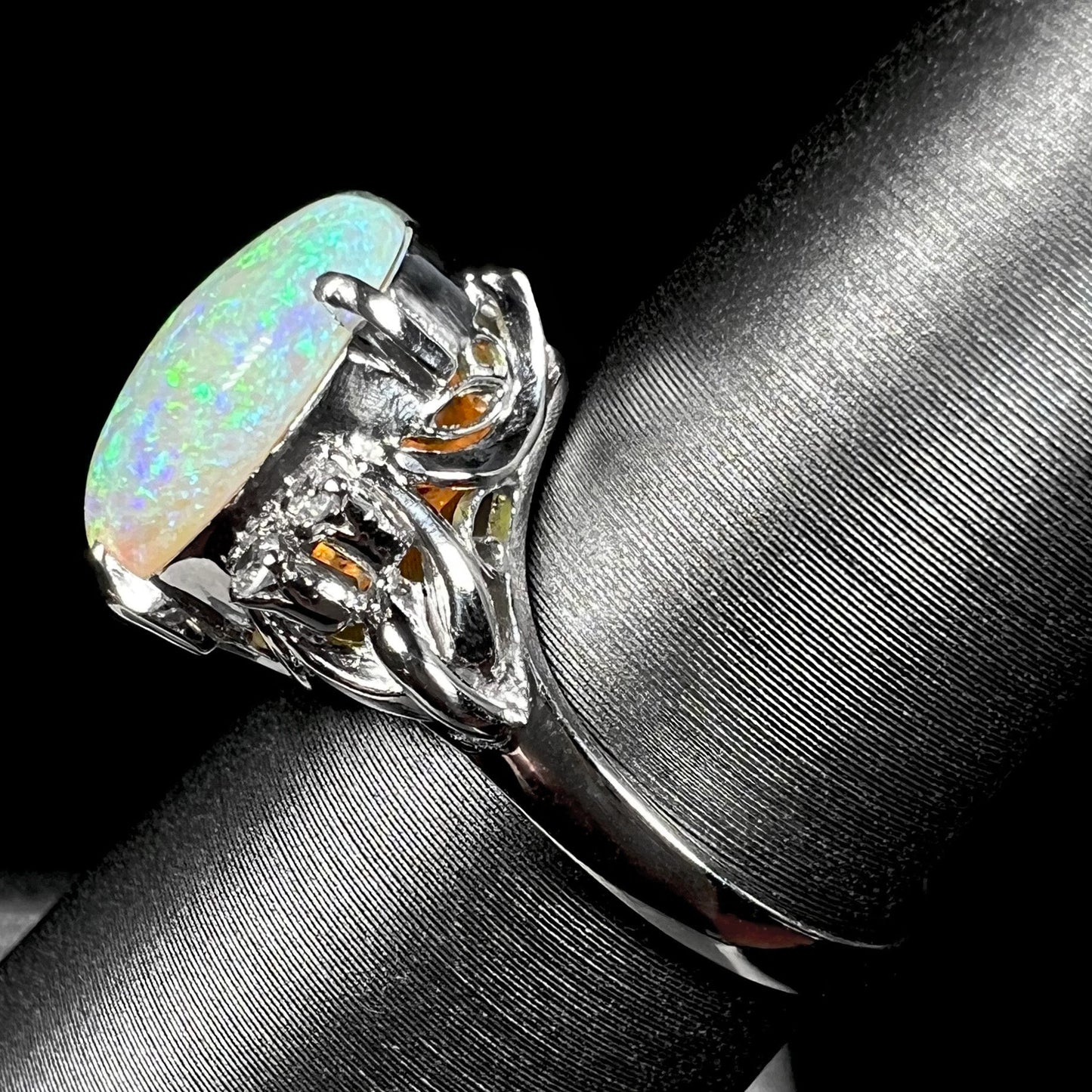 An Australian crystal opal and diamond engagement ring set in a platinum filigree mounting. The opal plays green/blue colors and has a crack.