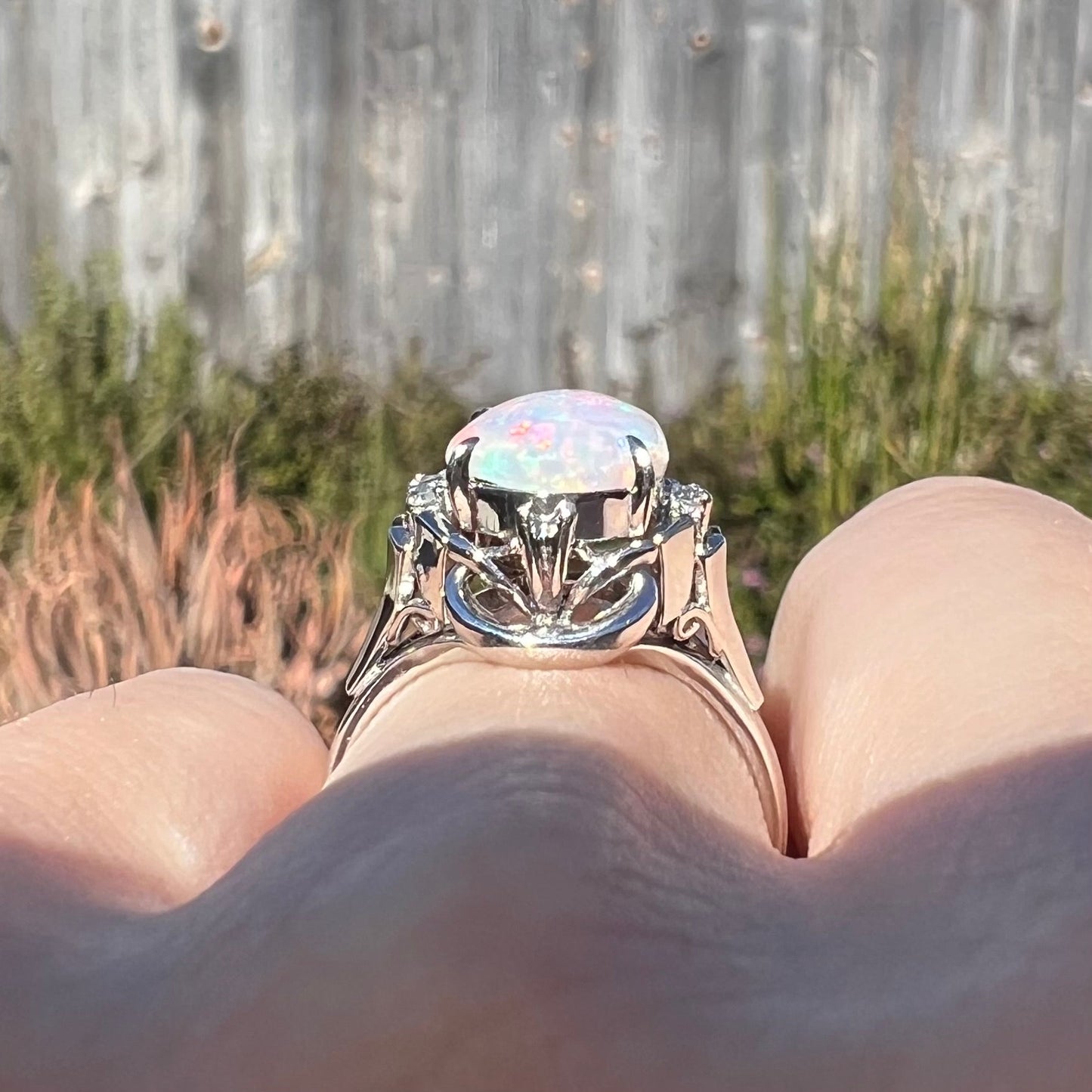 A platinum and diamond ring prong-set with an Australian opal. The opal has pink color play.