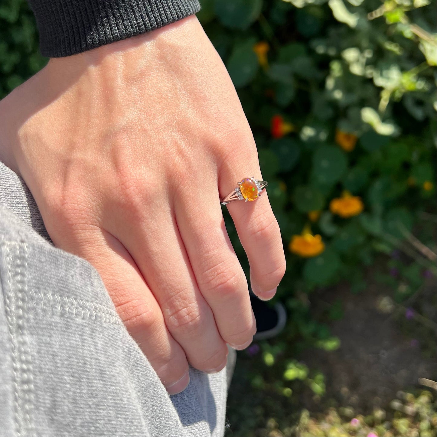 A platinum filigree and diamond-accented Mexican fire opal ring. The opal is orange with green fire.