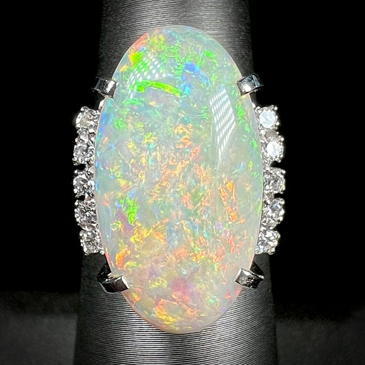 A platinum Coober Pedy opal cocktail ring lined with round brilliant cut accent diamonds.  The opal plays orange and green colors.