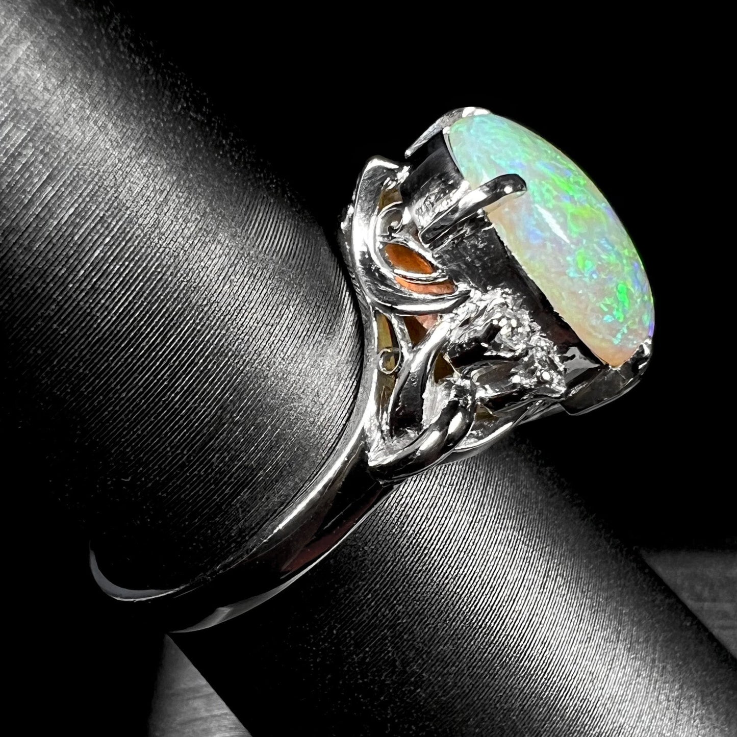 An Australian crystal opal and diamond engagement ring set in a platinum filigree mounting. The opal plays green/blue colors and has a crack.