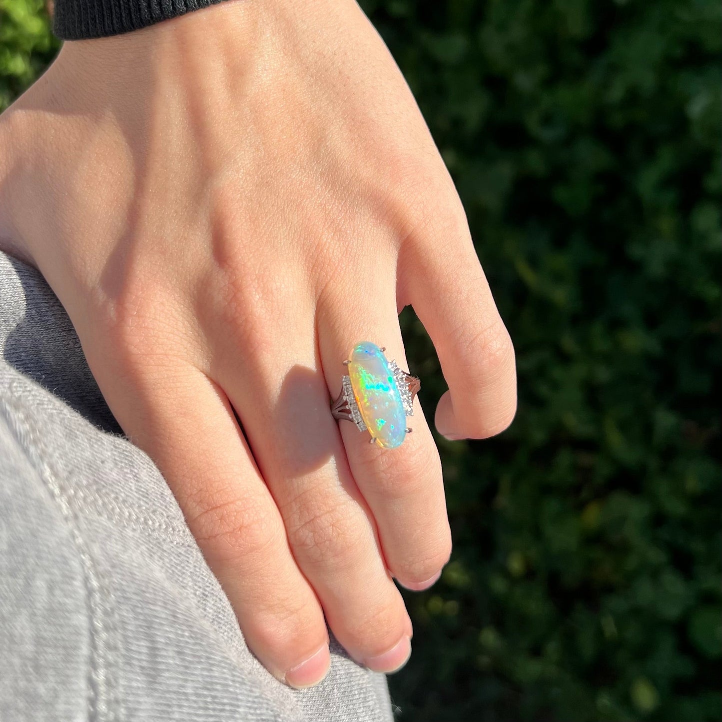 Person's hand resting on hip in natural light wearing Japanese heirloom Australian crystal opal and diamond statement ring