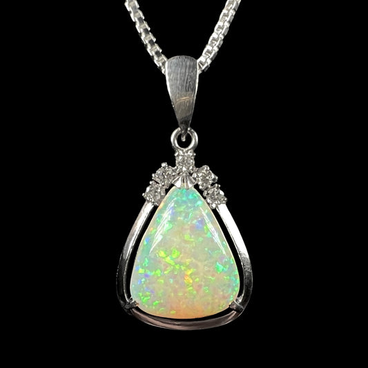 A platinum pinfire opal necklace with a green and blue fire pattern, captured in a macro shot against a black background.