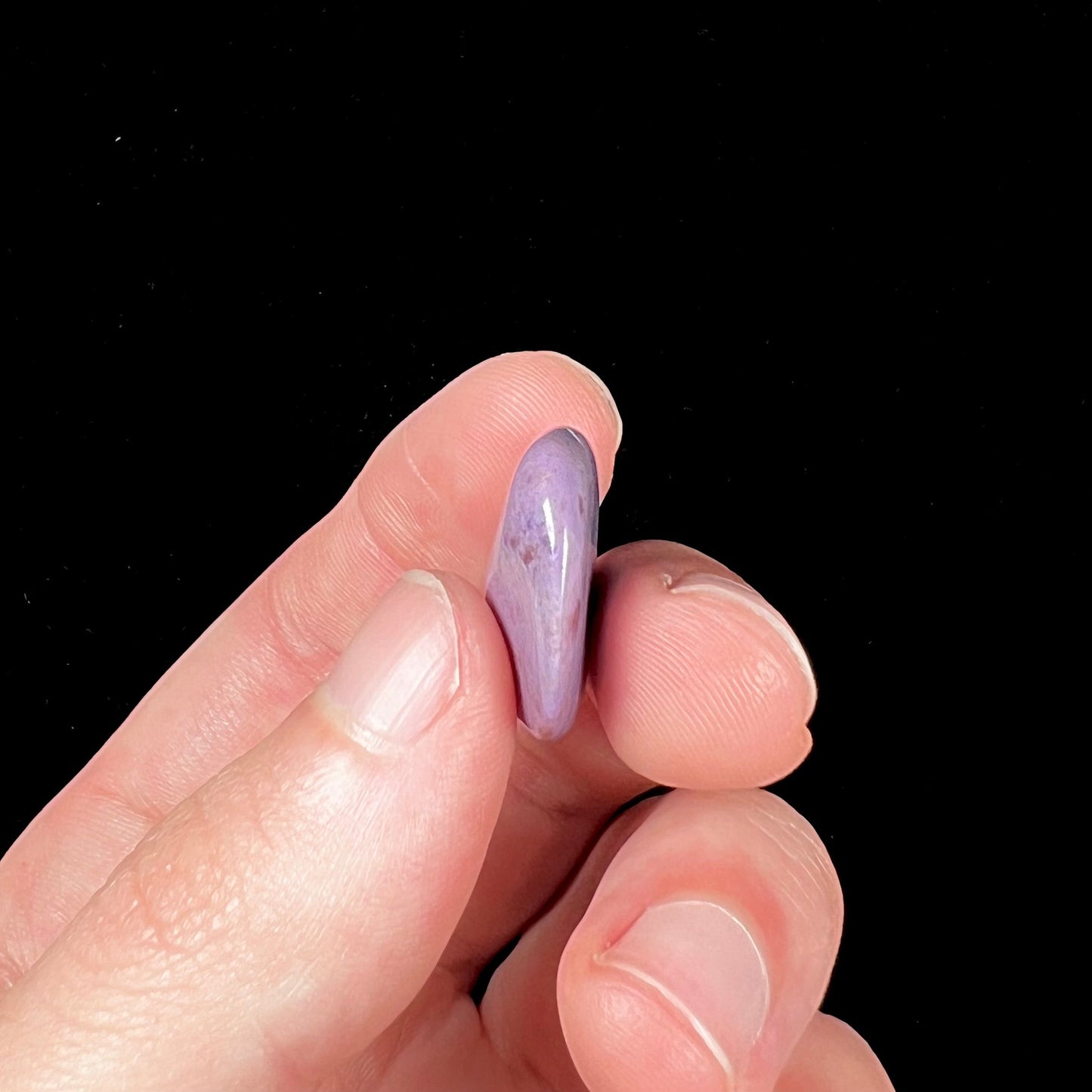 A tumbled turkiyenite jade stone from Bursa, Turkey. The rock is purple with red speckles.