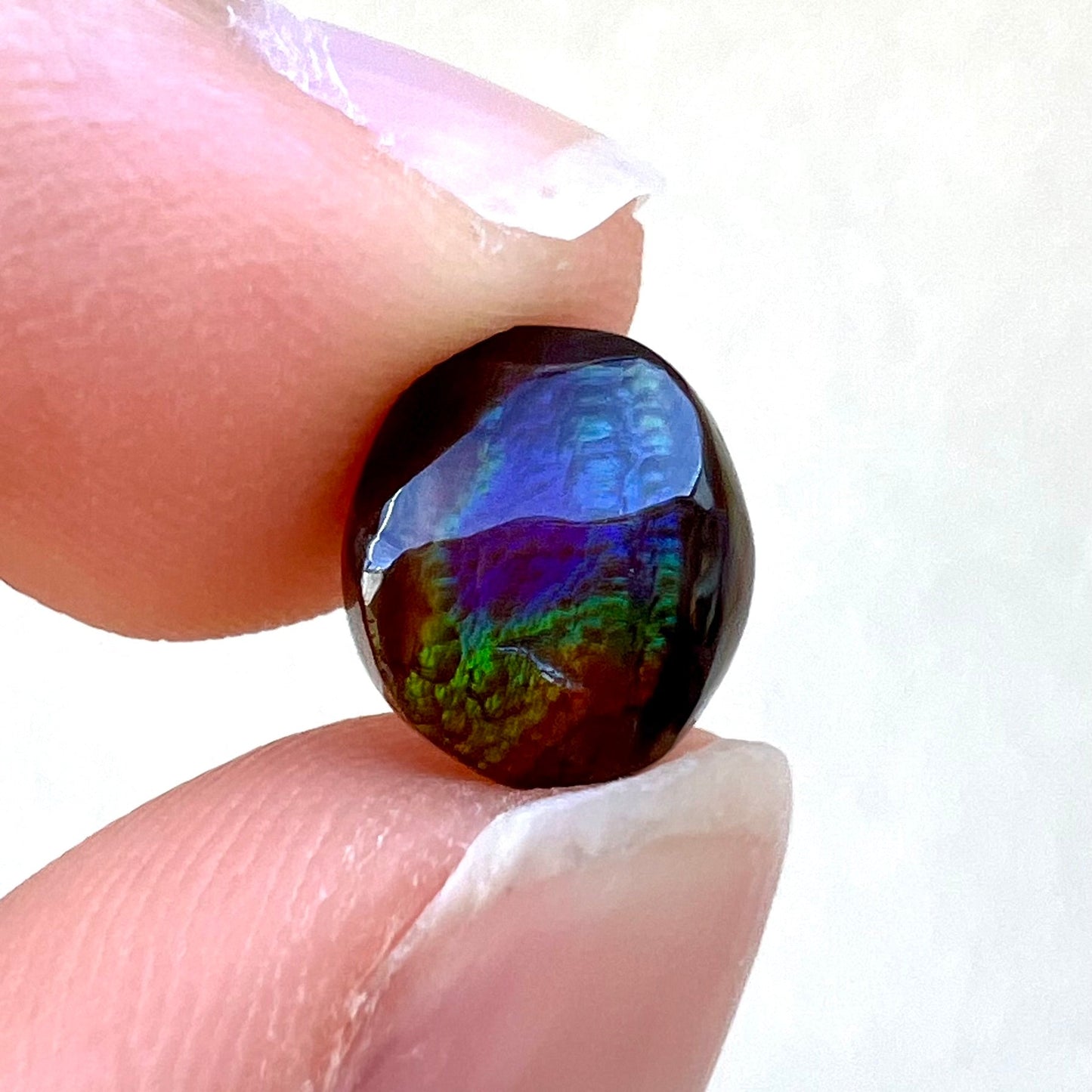 A loose, oval cabochon cut fire agate stone from Mexico. The stone has an iridescent purple and teal blue eye of color.