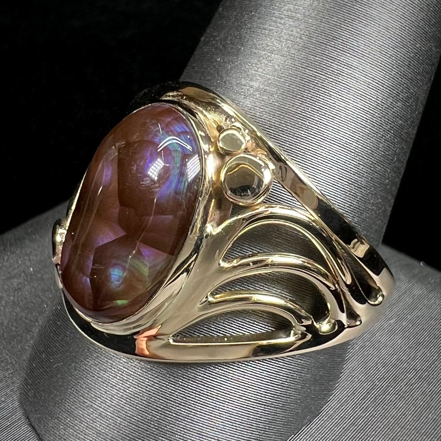 A men's yellow gold fire agate ring. The fire agate is blue and purple with light scratches.