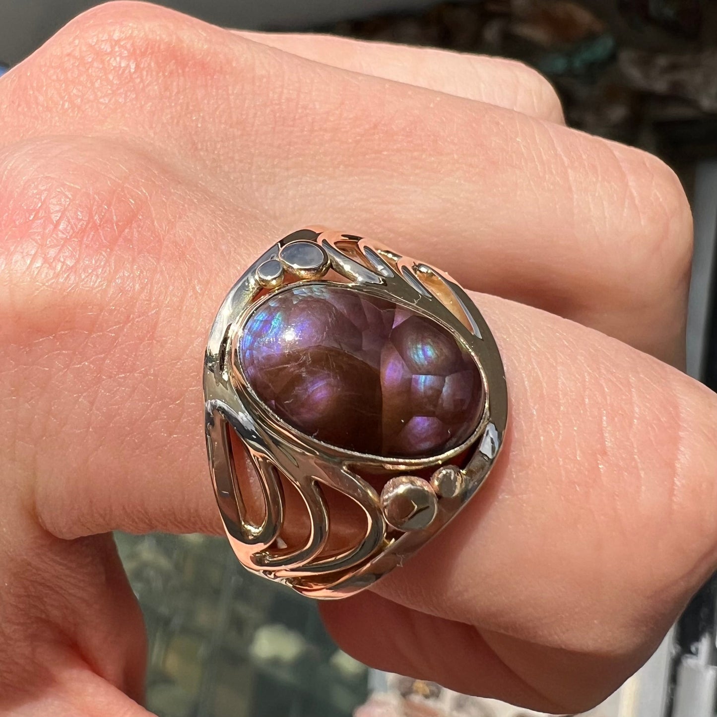 An oval cabochon cut fire agate with purple and blue colors set in a yellow gold men's ring.