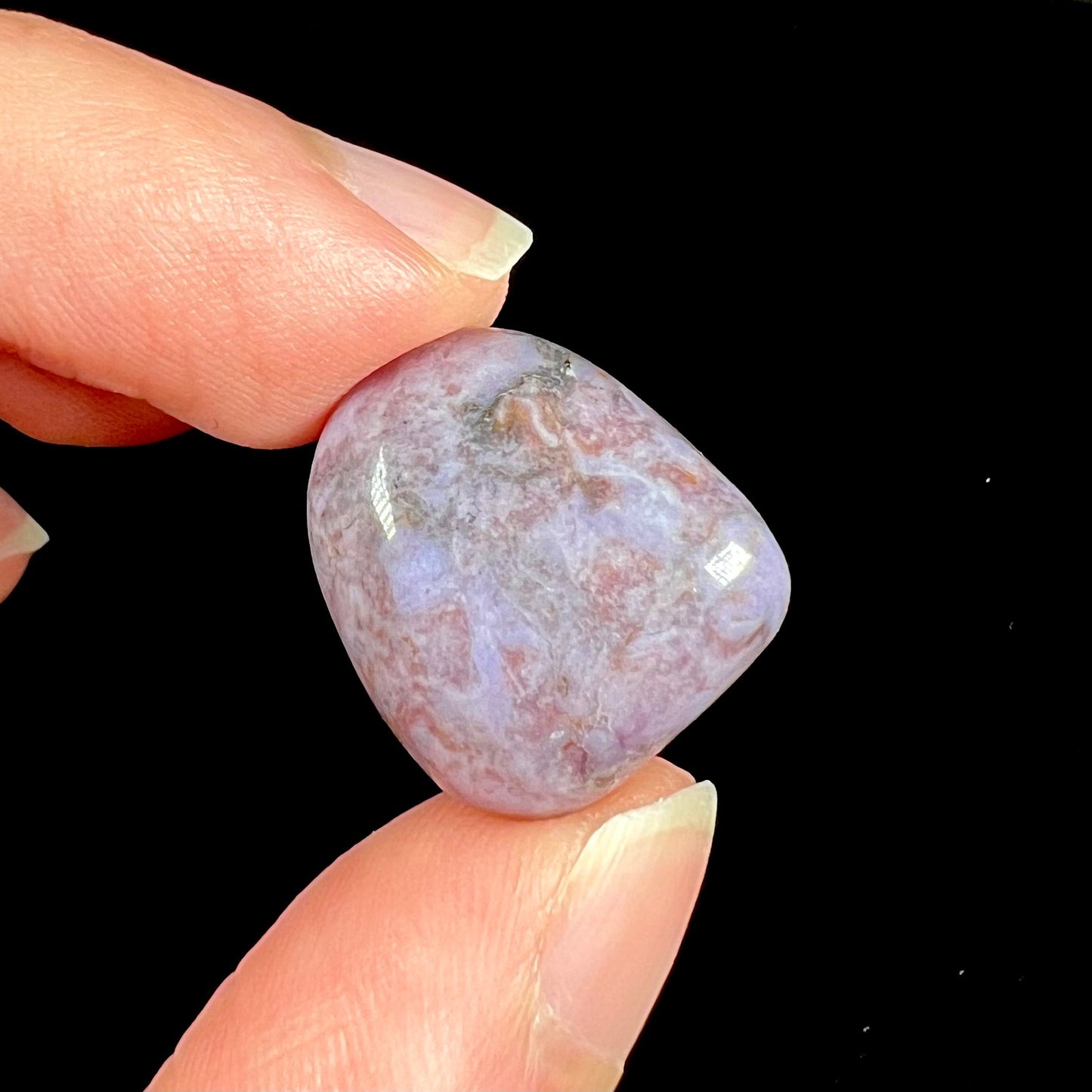 A tumble polished turkiyenite purple jade stone from Bursa, Turkey. Material has reddish marbling.