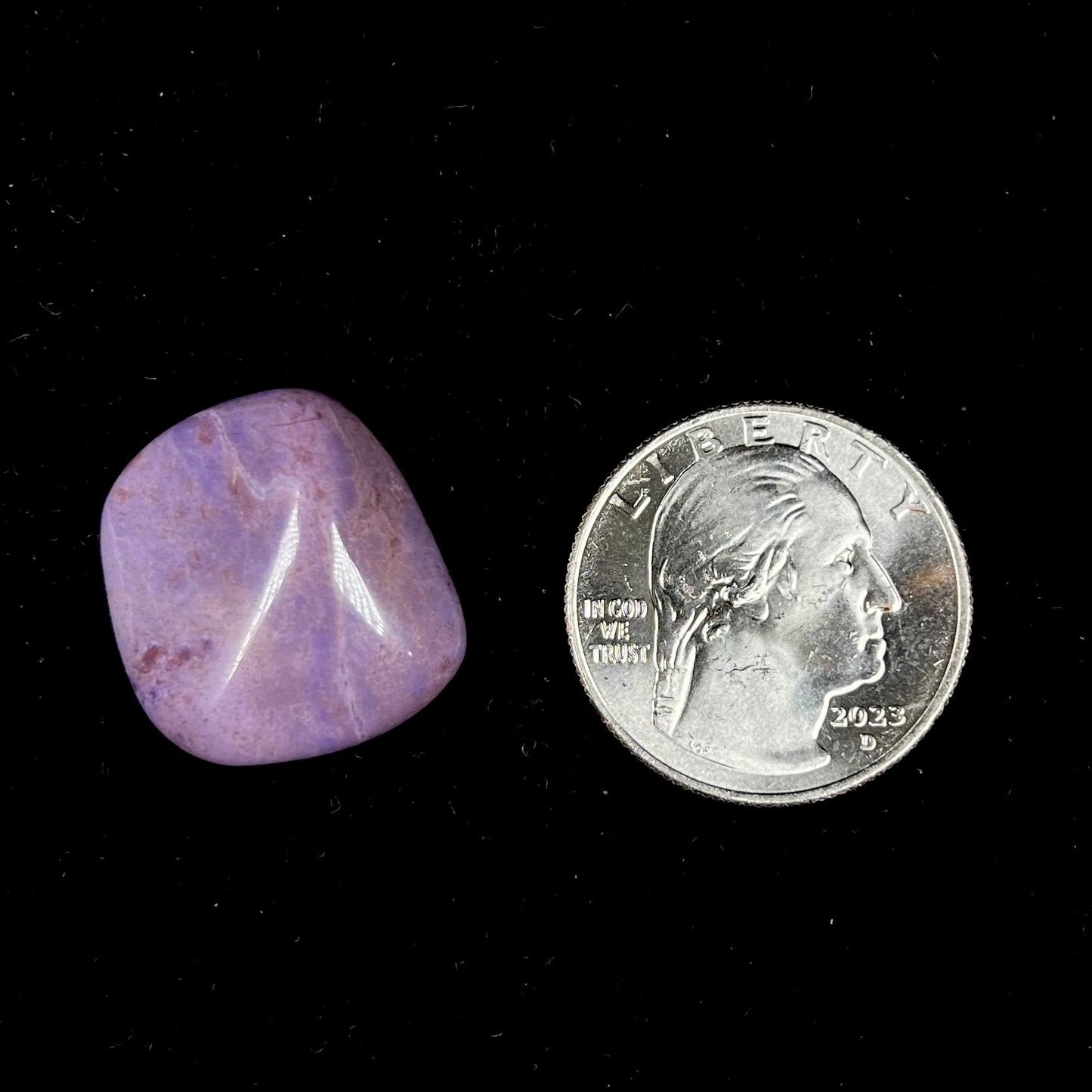 A tumbled turkiyenite jade stone from Bursa, Turkey. The rock is purple with red speckles.