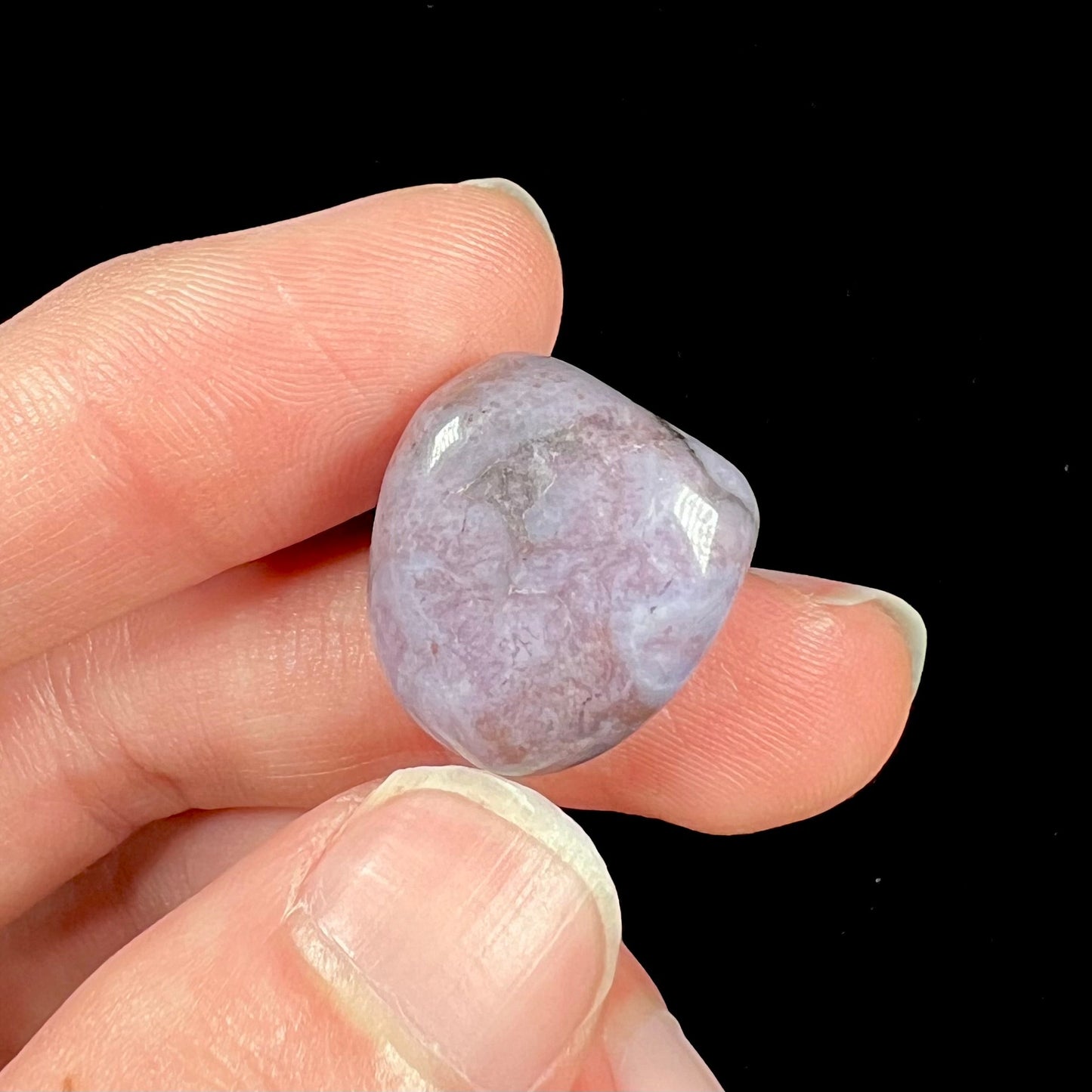 A tumble polished turkiyenite purple jade stone from Bursa, Turkey. Material has reddish marbling.