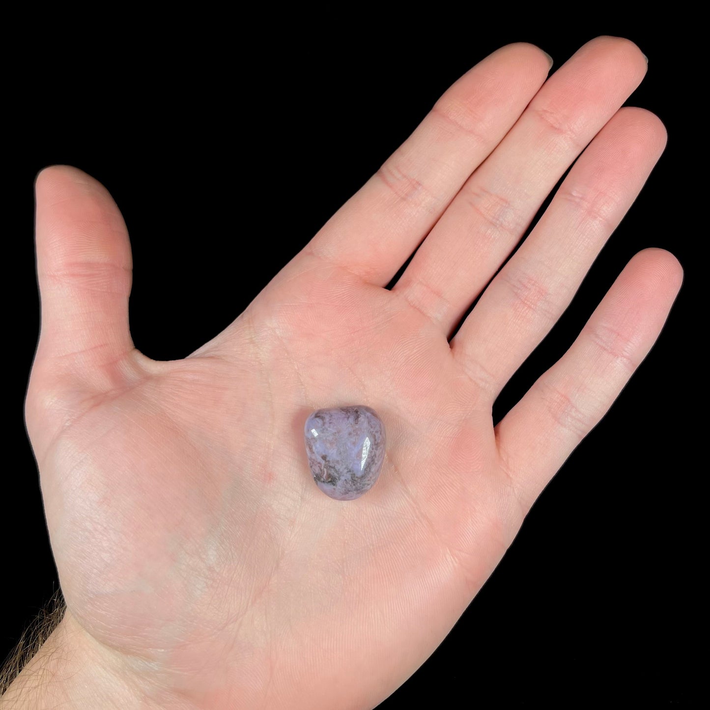 A tumble polished turkiyenite purple jade stone from Bursa, Turkey. Material has reddish marbling.