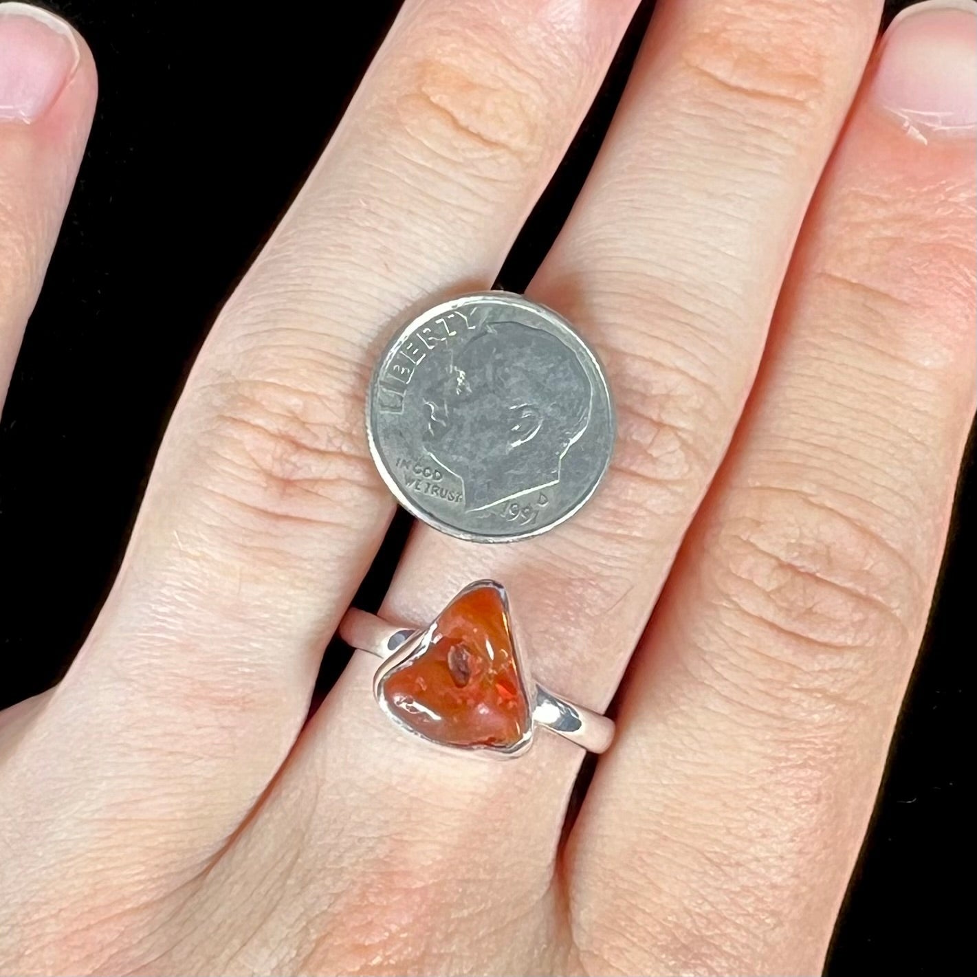 A polished fire opal crystal bezel set into a sterling silver ring. The opal is an orange color.
