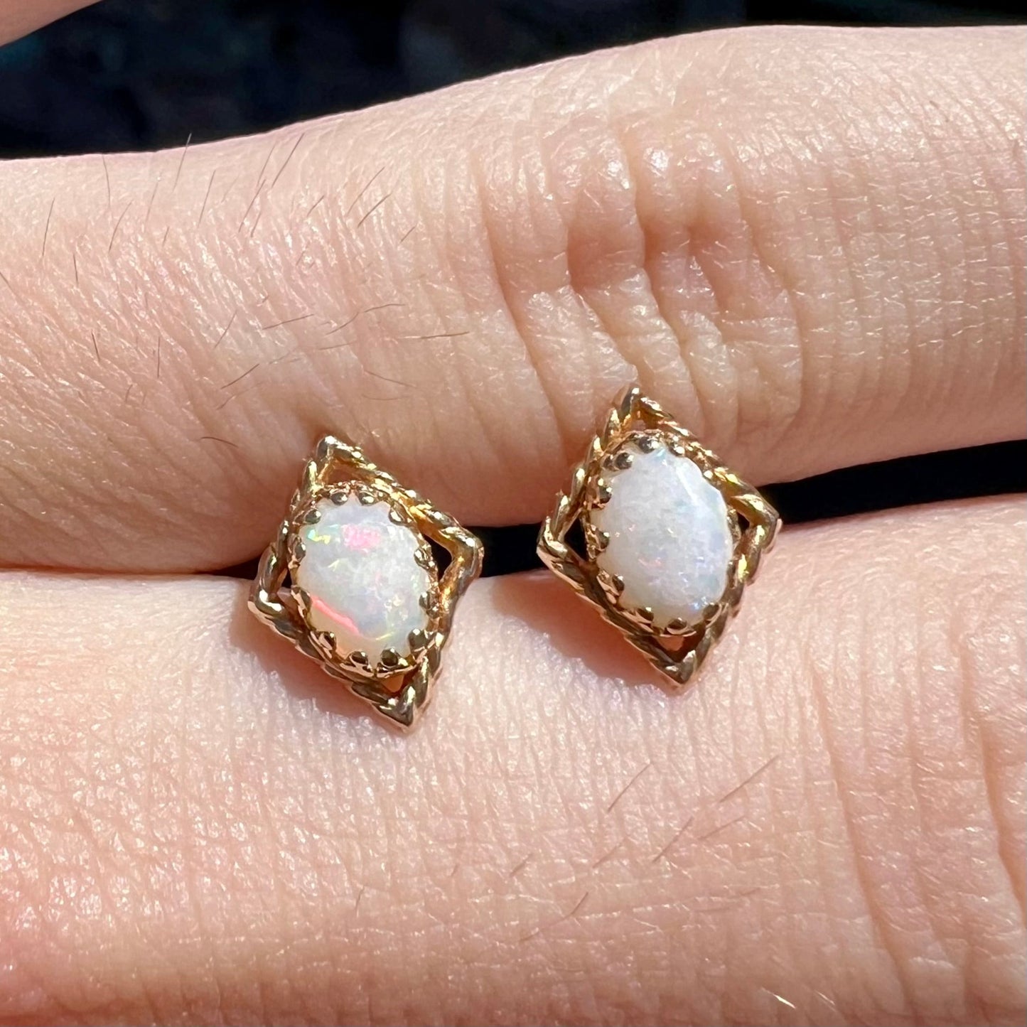 A pair of opal stud earrings. The opals are set in yellow gold diamond shaped mountings.