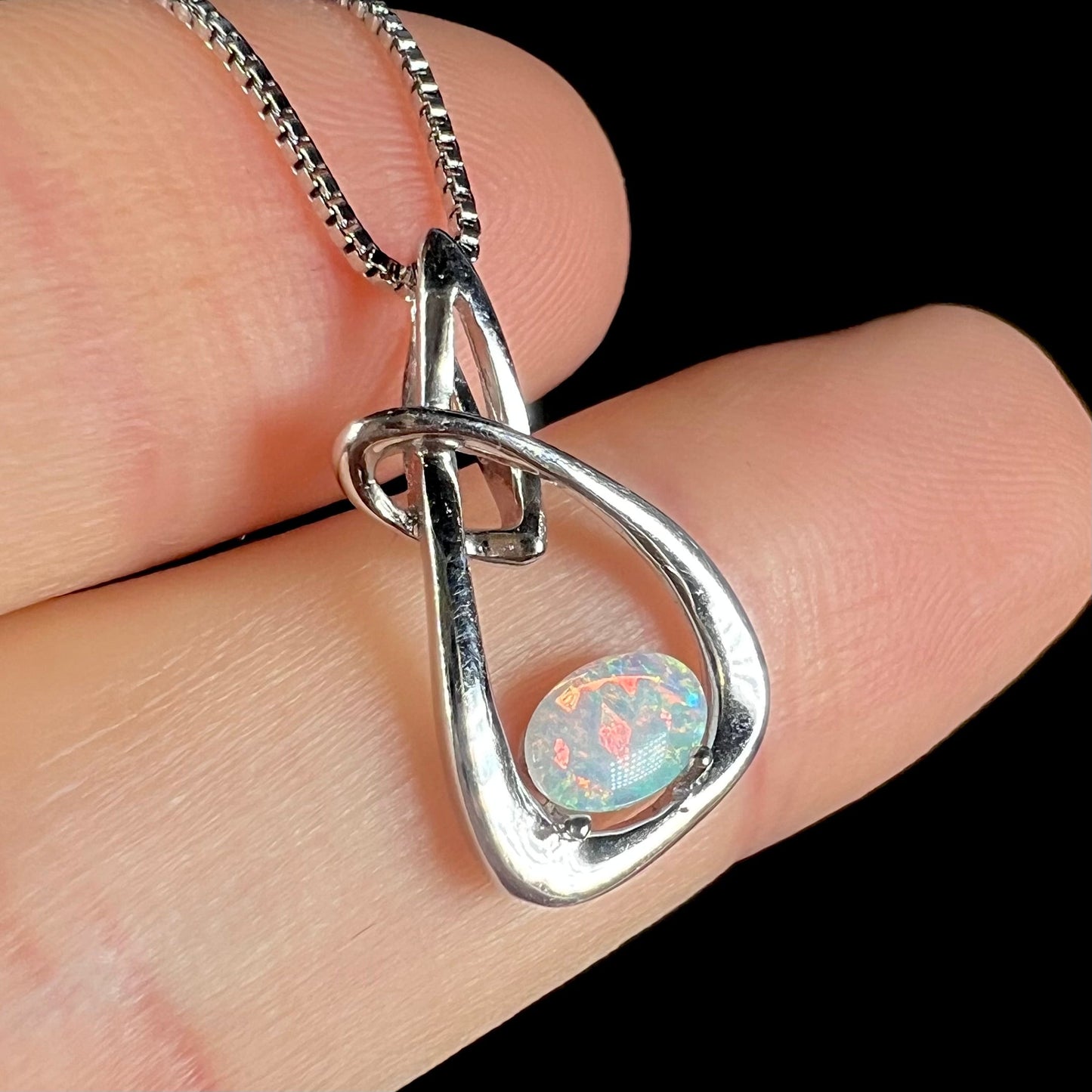 A ladies' sterling silver pendant set with an oval cabochon cut natural white crystal opal.