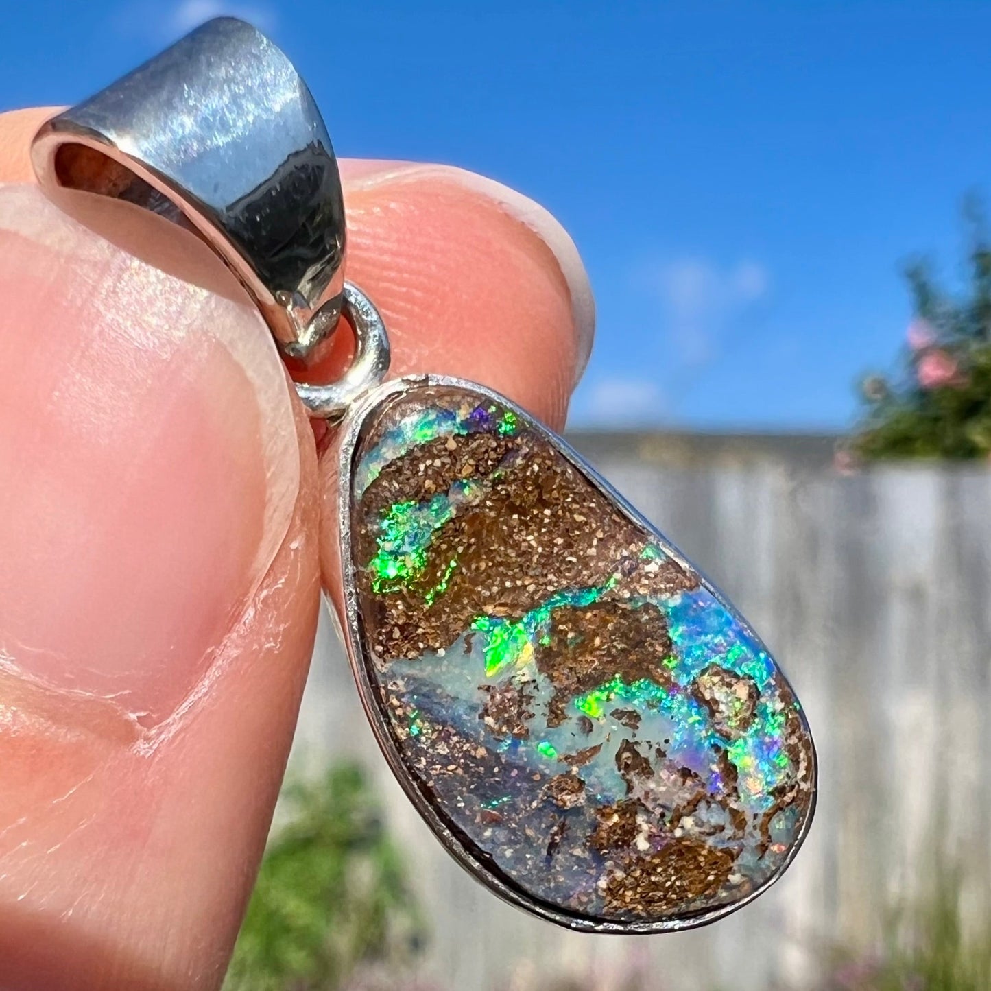 A sterling silver necklace set with a rainbow boulder opal stone.
