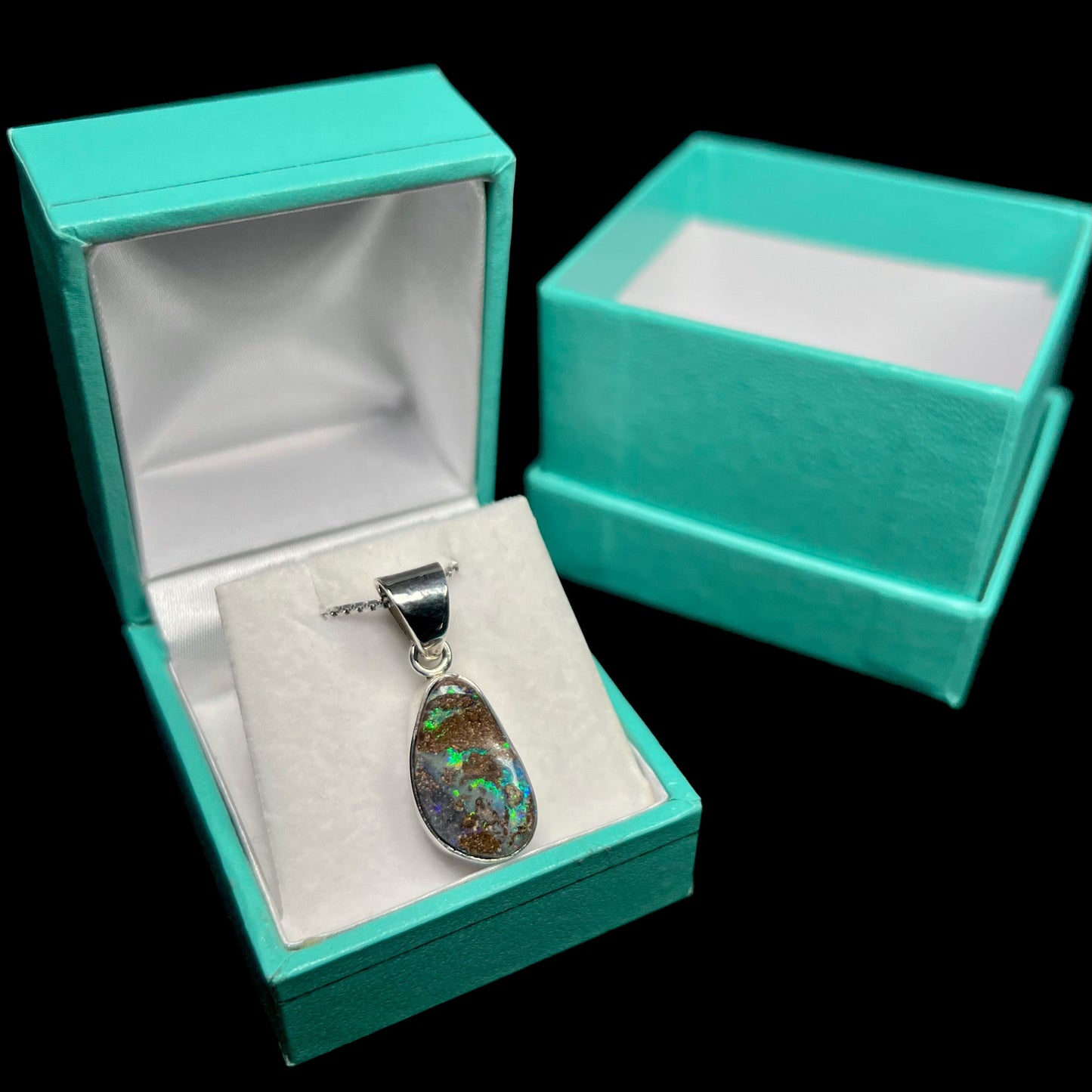 A sterling silver pendant set with an Australian boulder opal on a silver box chain.