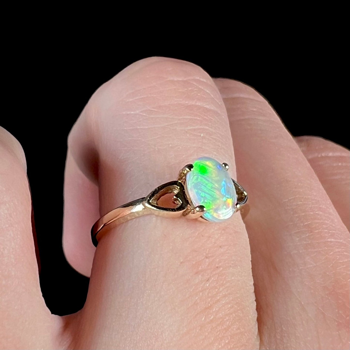 A dainty yellow gold ring mounted with a vivdly bright red Australian opal. The ring has two heart shaped designs.