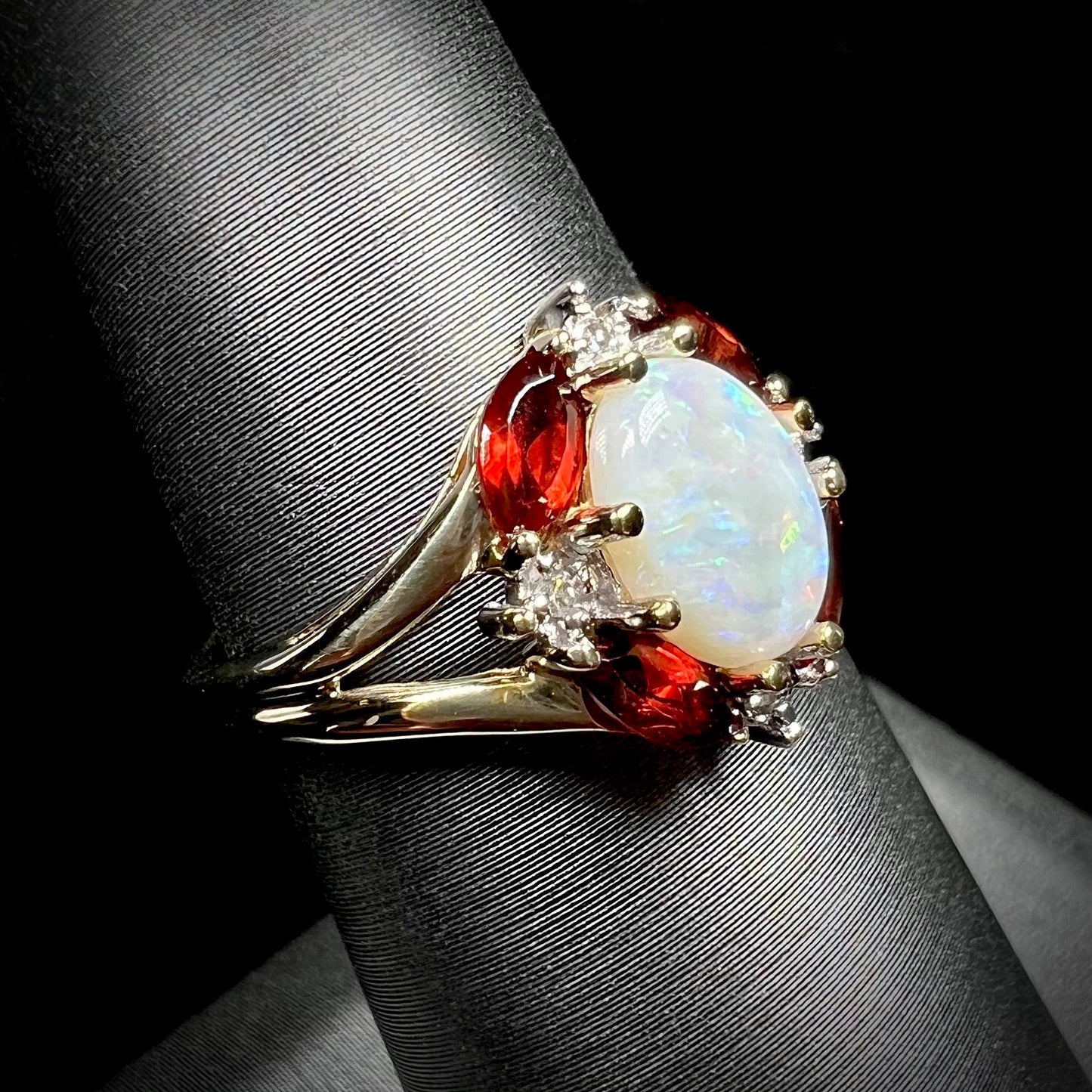 A ladies natural opal ring in yellow gold. The opal is surrounded by red marquise cut garnets and diamonds.