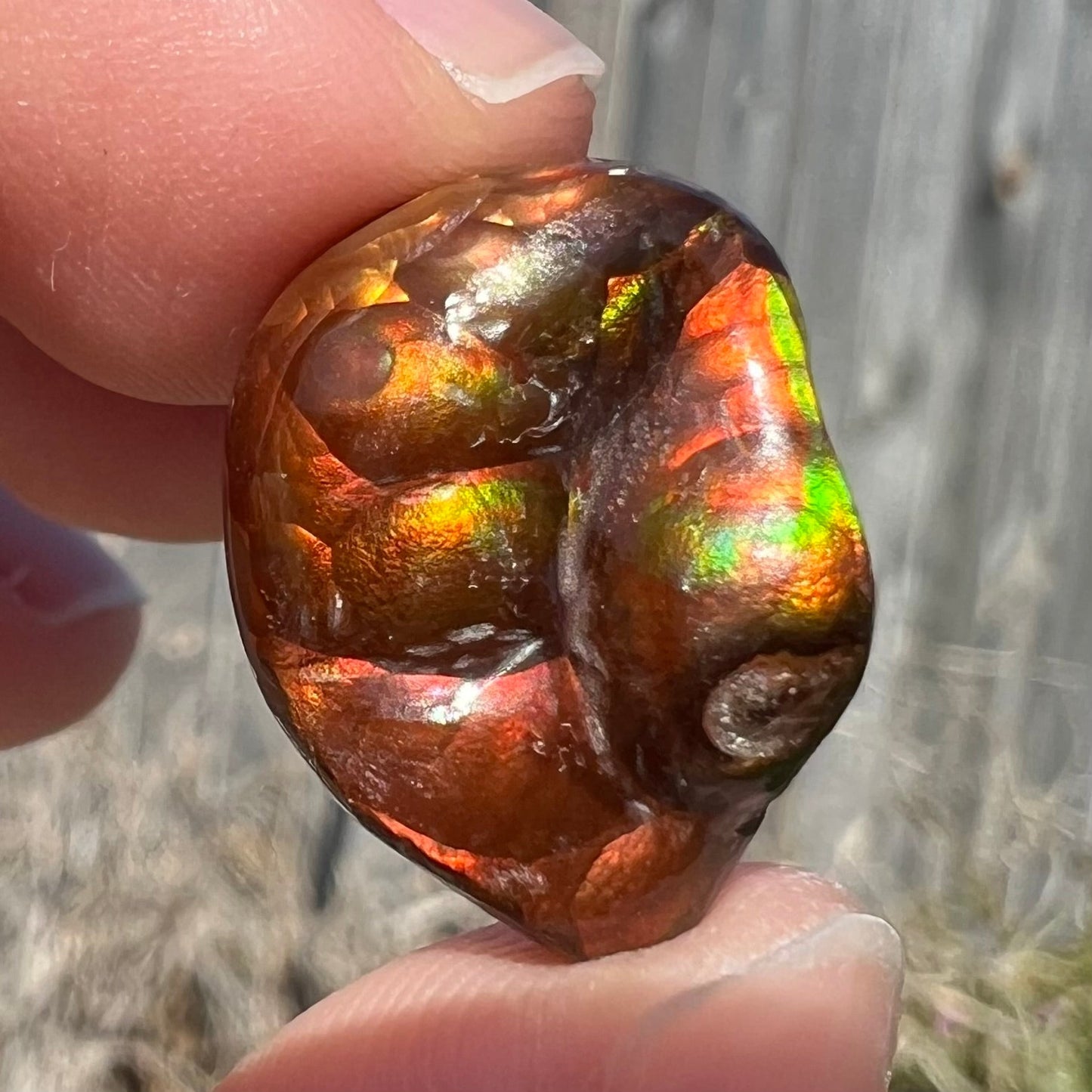 A large Mexican fire agate gemstone. The stone is red with green iridescence and a waxy luster.