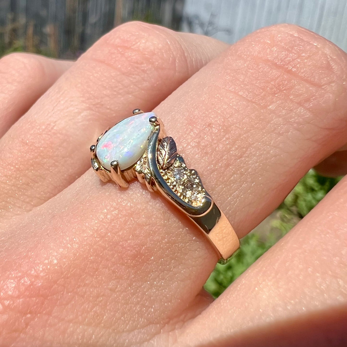 A ladies' two-tone yellow and rose Black Hills gold opal and diamond ring. The opal is a pear shaped cabochon.