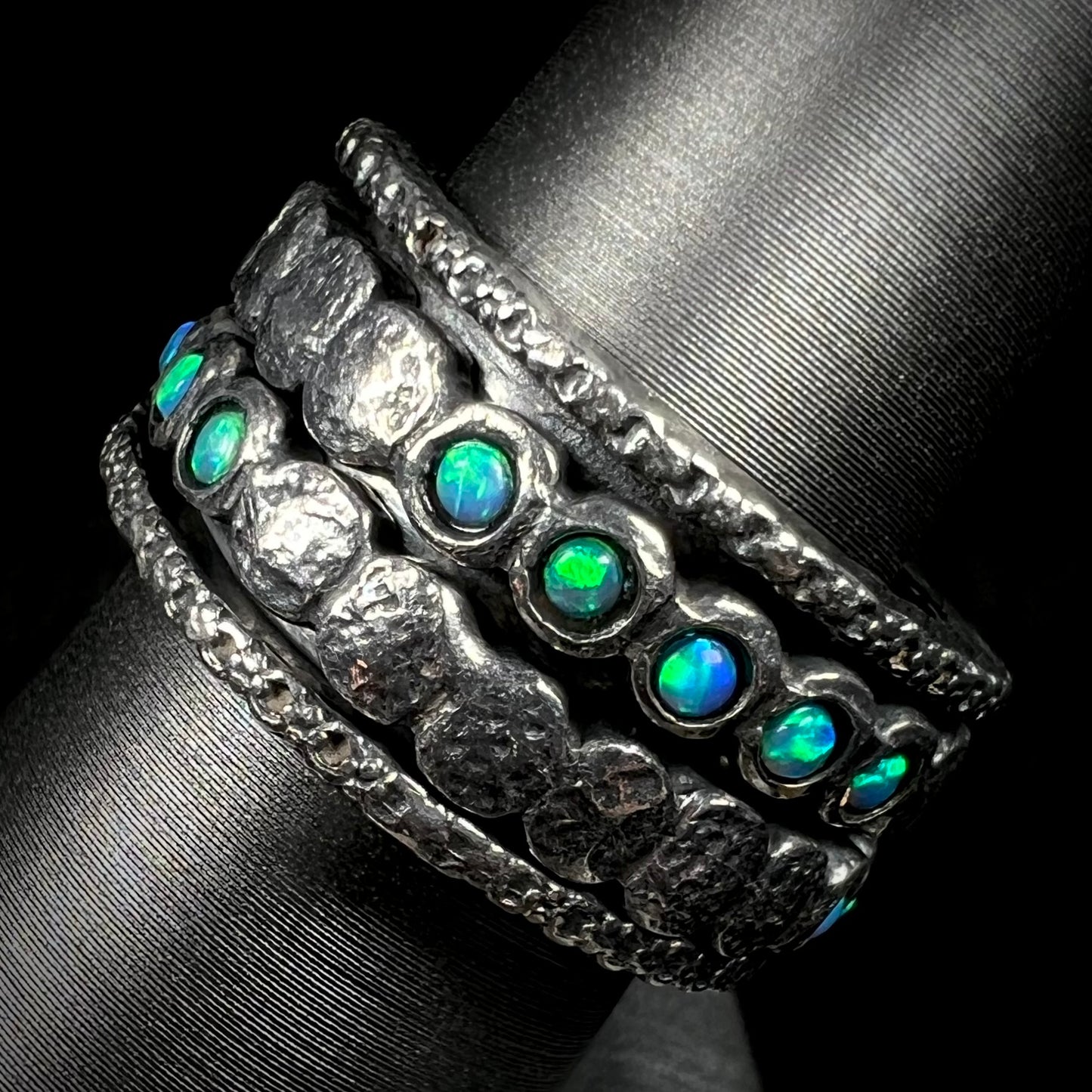 Side view of round opals with green color play, mounted into a silver spinner ring for men.