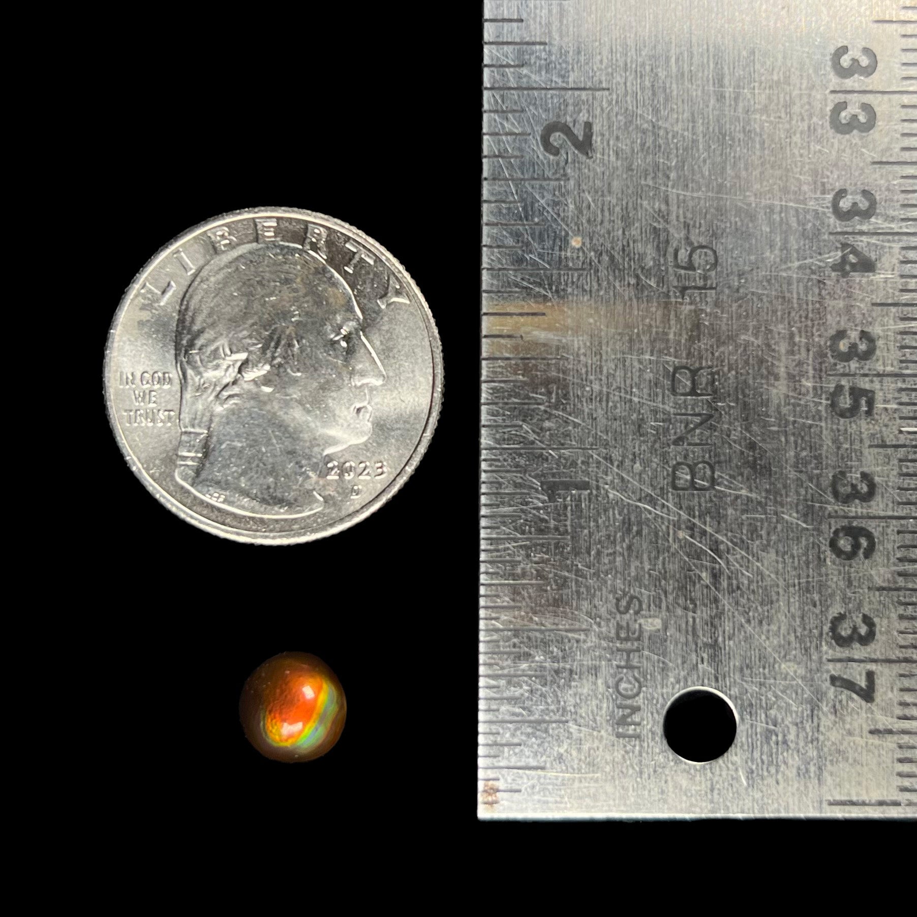 A 1.69ct round cabochon cut Mexican fire agate stone.  The stone is red with purple and green swirls.