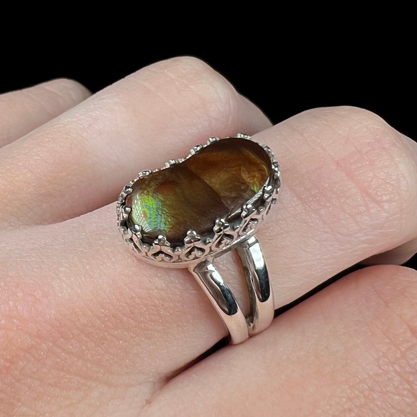Close-up angled view of finger wearing a silver fire agate ring with a royal design. The prongs have a crown motif.