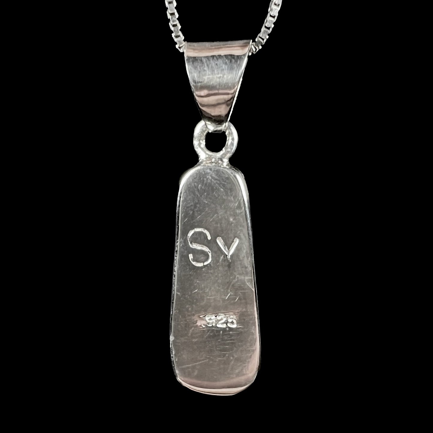 A sterling silver necklace bezel set with a natural Australian boulder opal stone. The stone shines colors of blue, green, and purple.