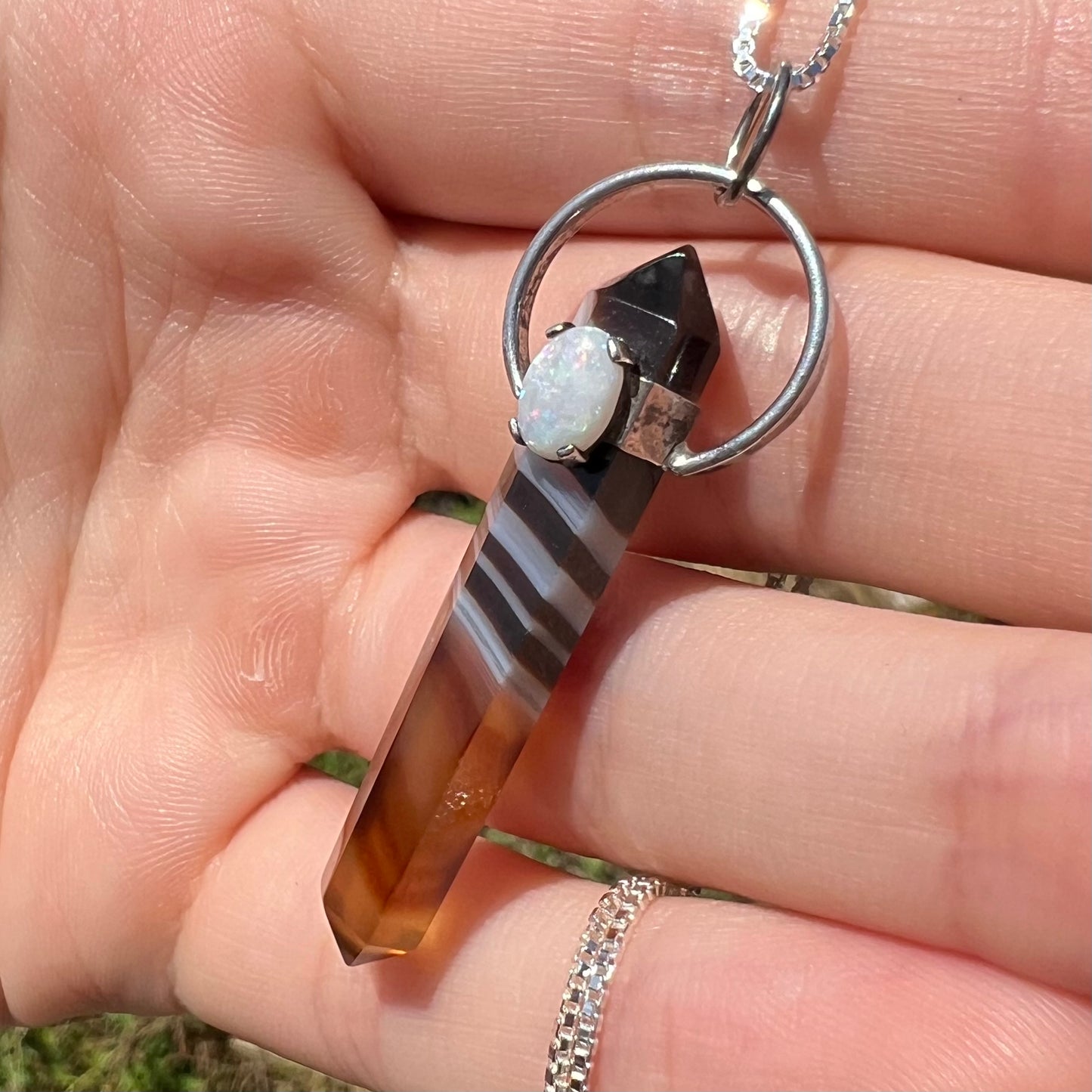 Angled natural light close-up of a sardonyx and opal necklace.
