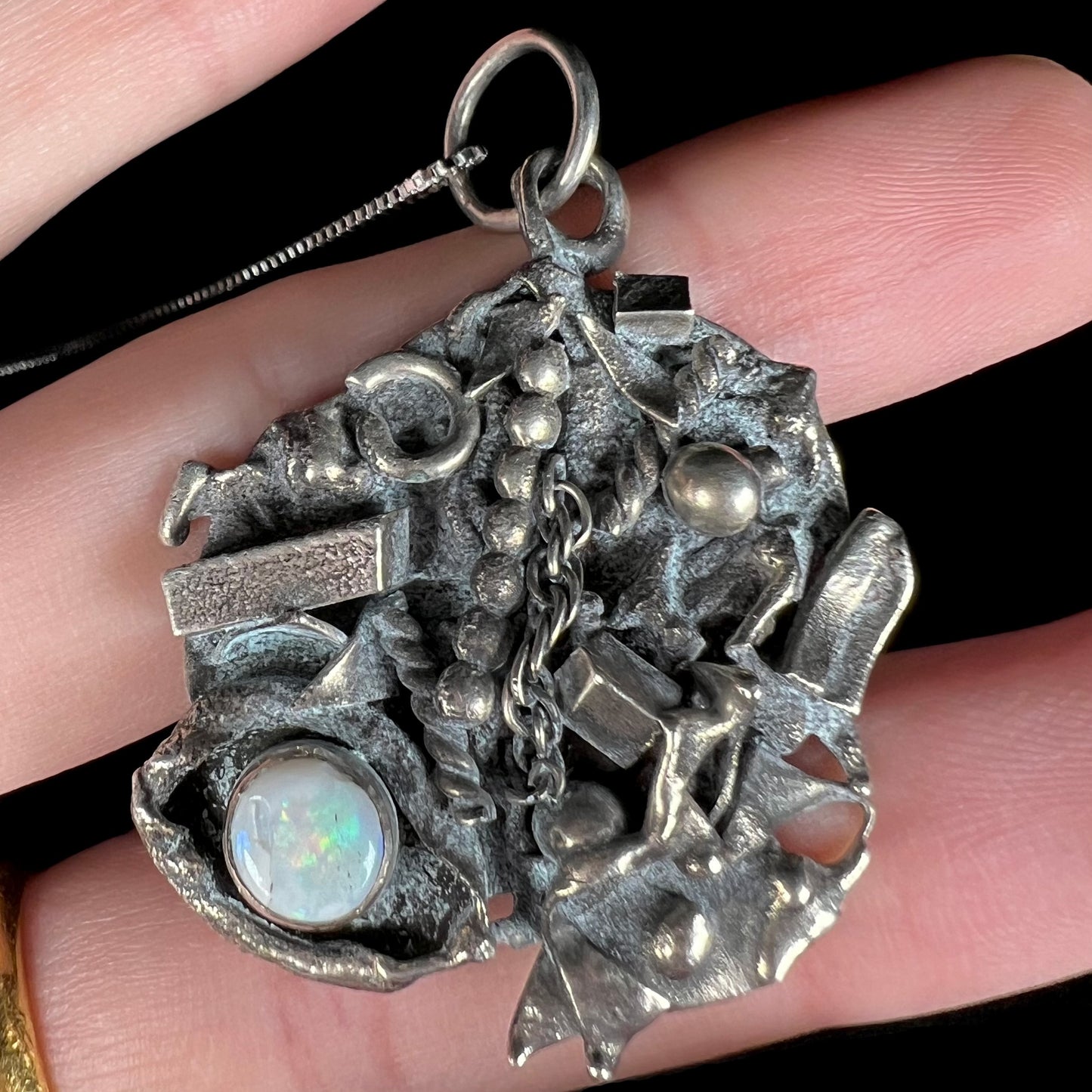 A scrap silver opal shipwreck necklace shown close-up from the front view.