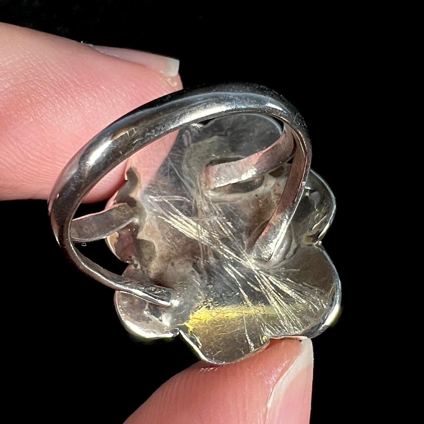 Scratched back of vintage sterling silver fire agate ring shown up close.