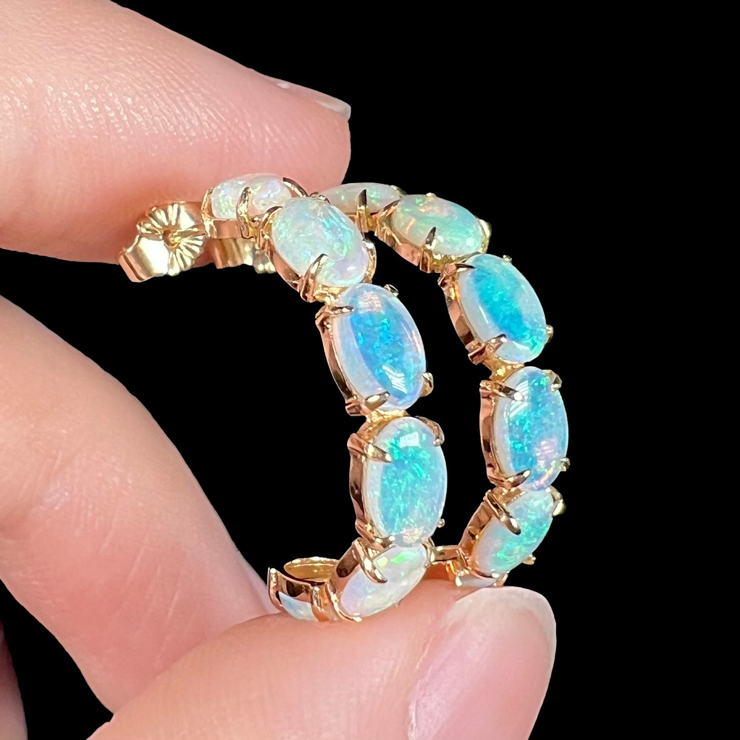Angled macro view of opal semi-hoops showing both the face and side of the earrings.