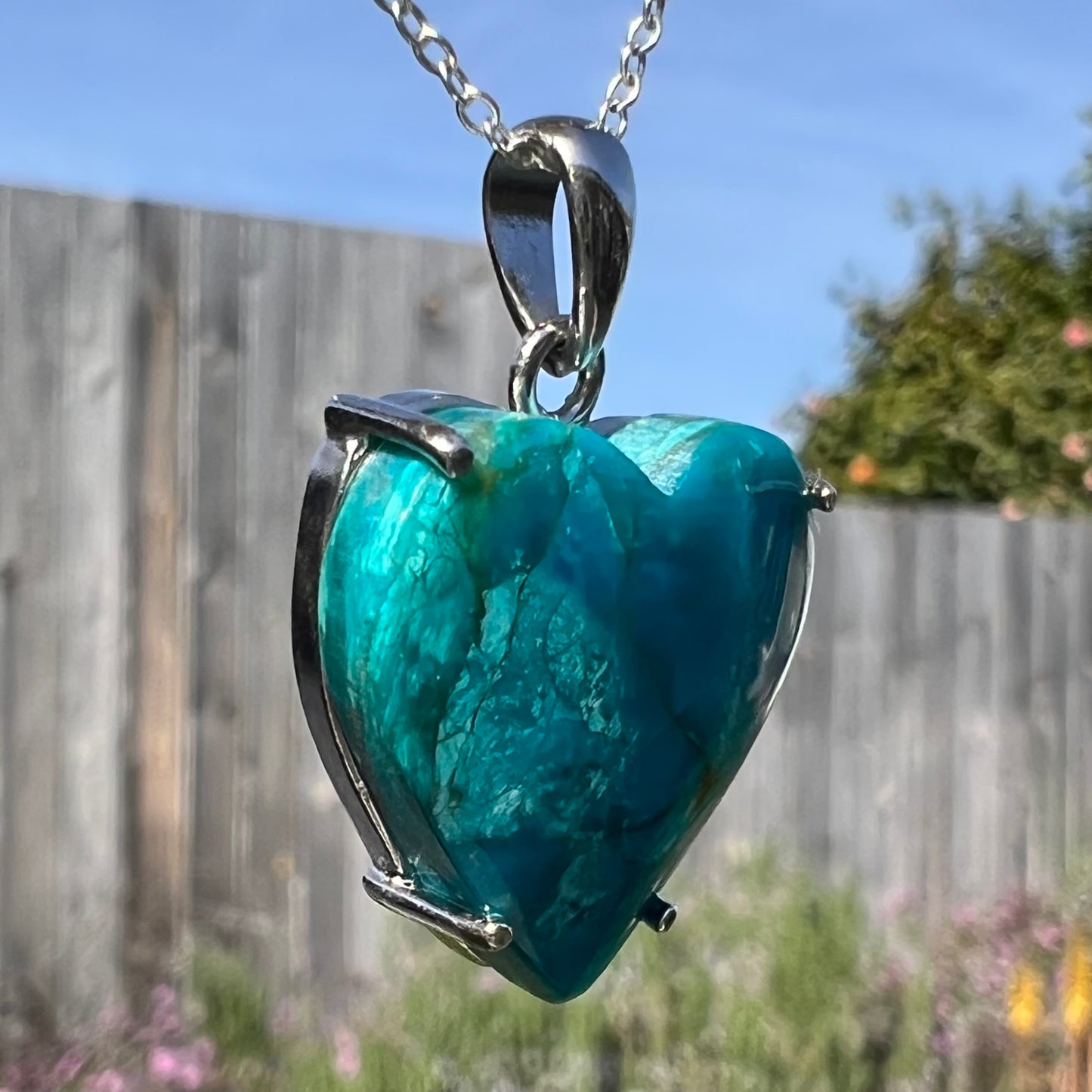 Close-up angled shot of shaded opal heart necklace with textured blue coloring.