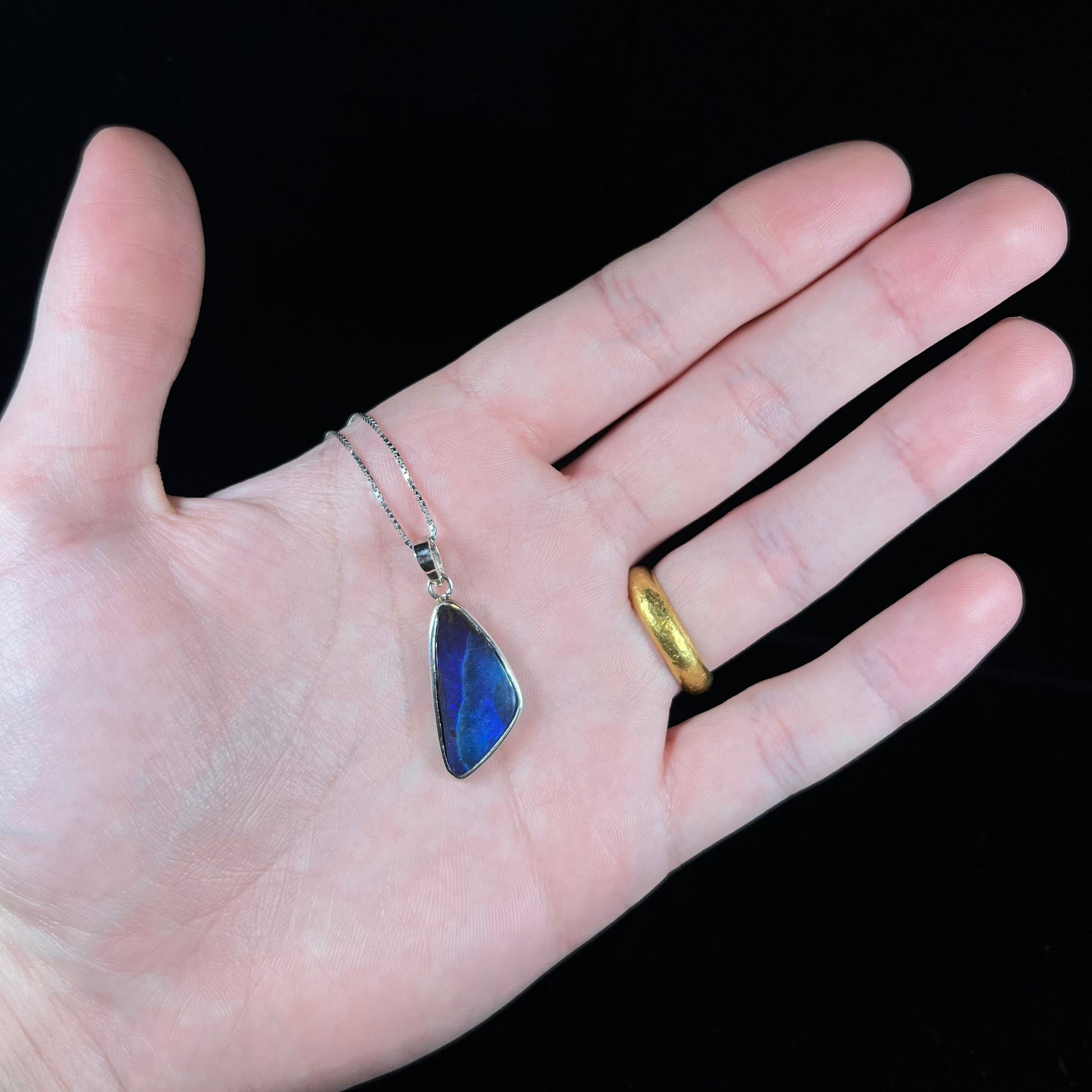 A ladies' sterling silver necklace bezel set with a triangle drop shaped Australian black boulder opal.